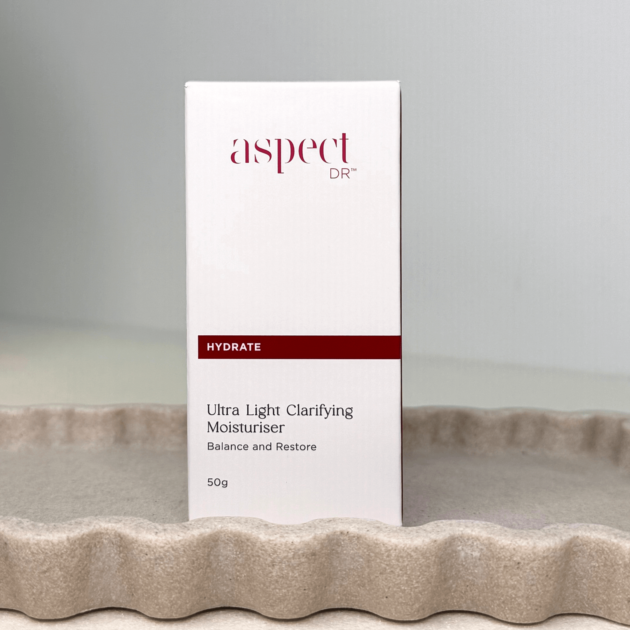 Aspect Dr Ultra Light Clarifying moisturiser front of packaging sitting on scalloped tray on a neutral background
