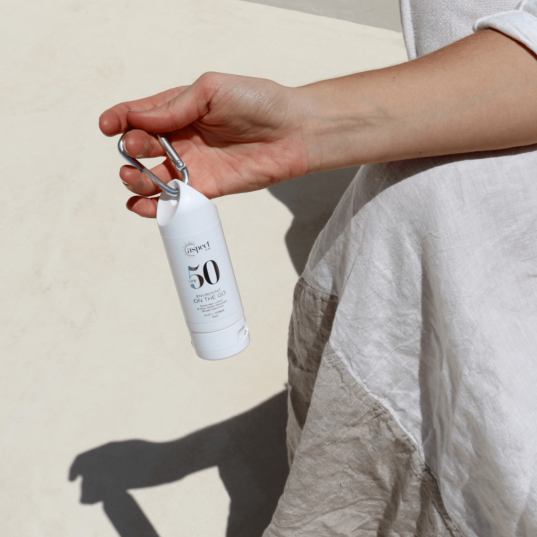 On the Go spect sun skincare held outside on beige background