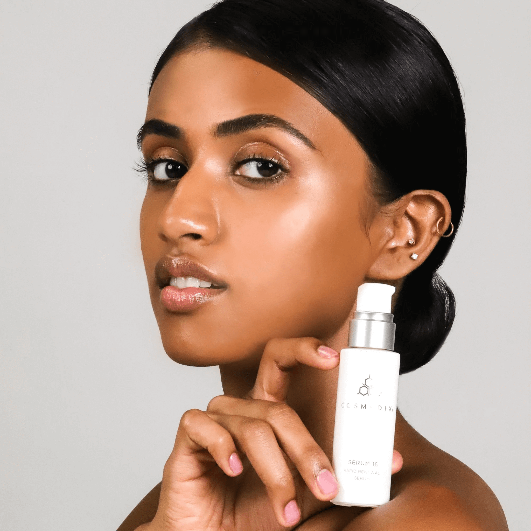 Woman holding Serum 16 bottle on light grey background