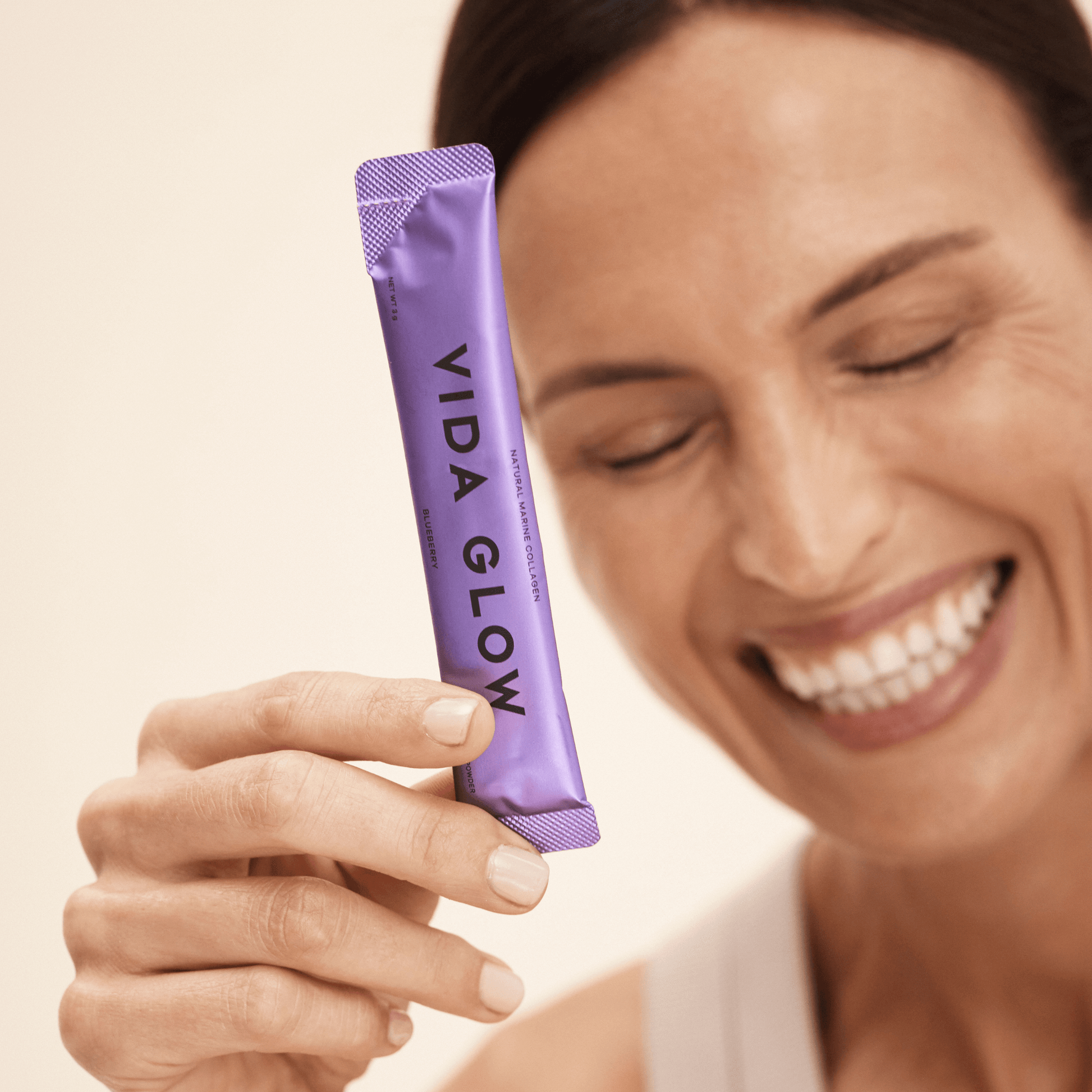 Vida Glow Blueberry powder sachet held by model