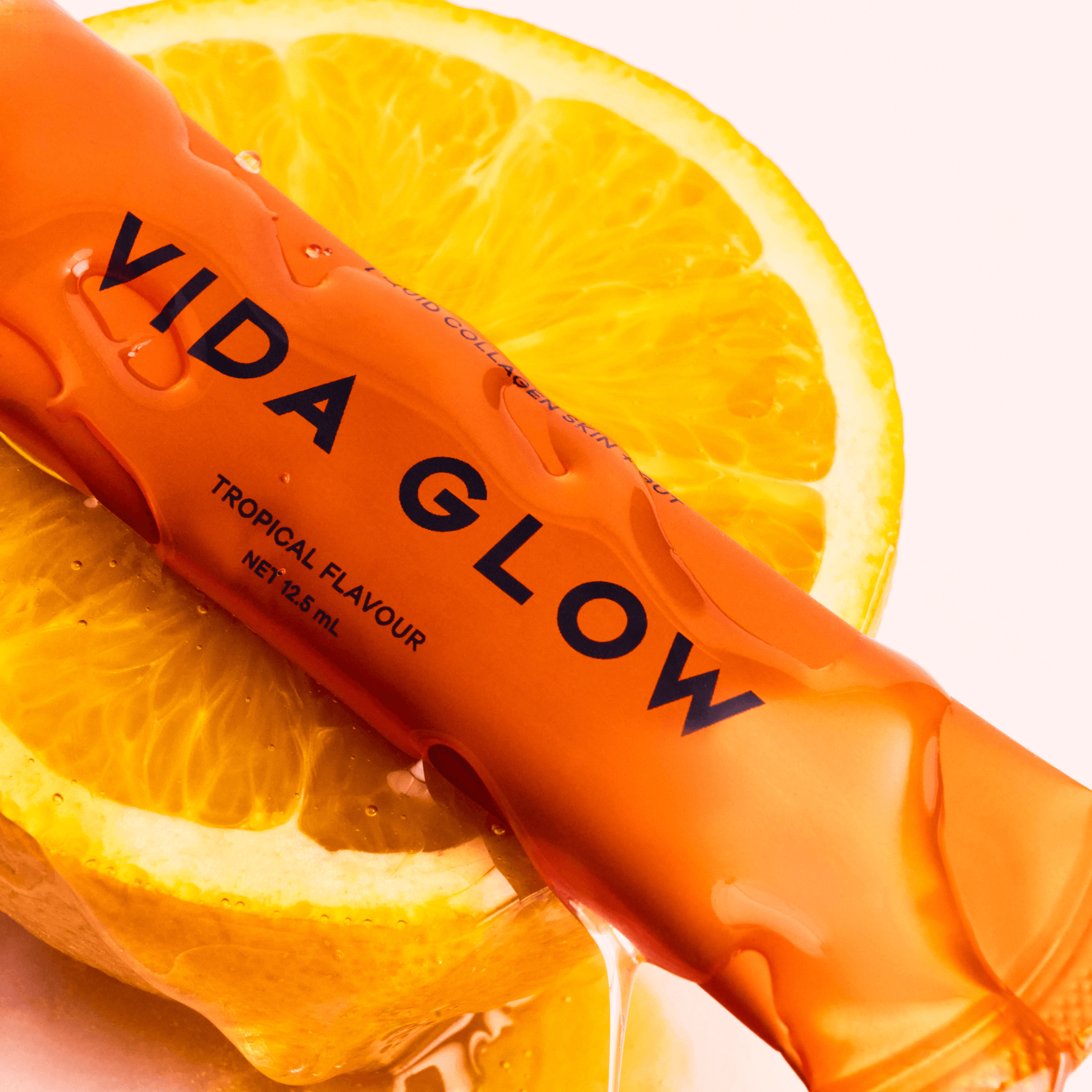 Vida Glow tropical flavour sachet on an orange slice with a white background
