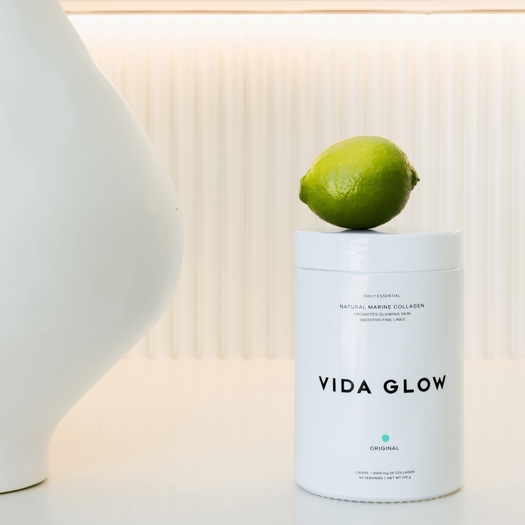 Vida Glow collagen powder large tub with lime resting on jar
