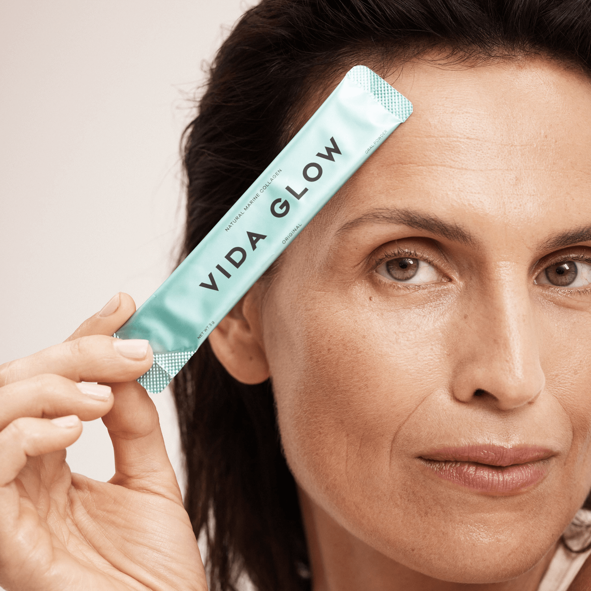 Vida Glow original collagen sachet held over face by model