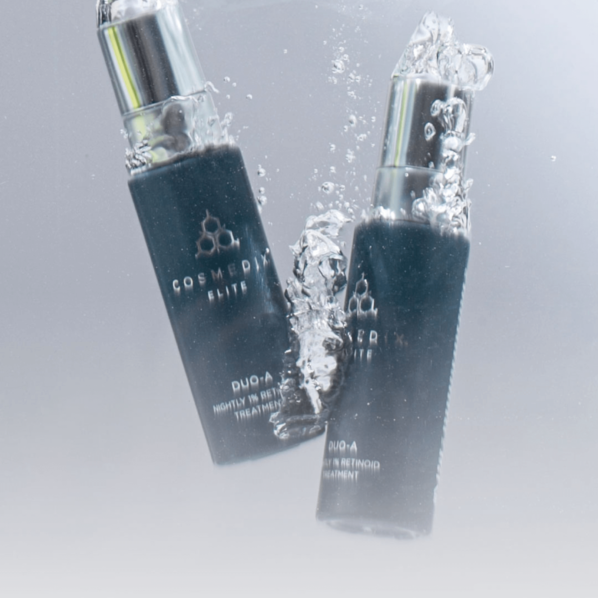 Two COSMEDIX ELITE Duo-A bottles submerged in water on a grey background
