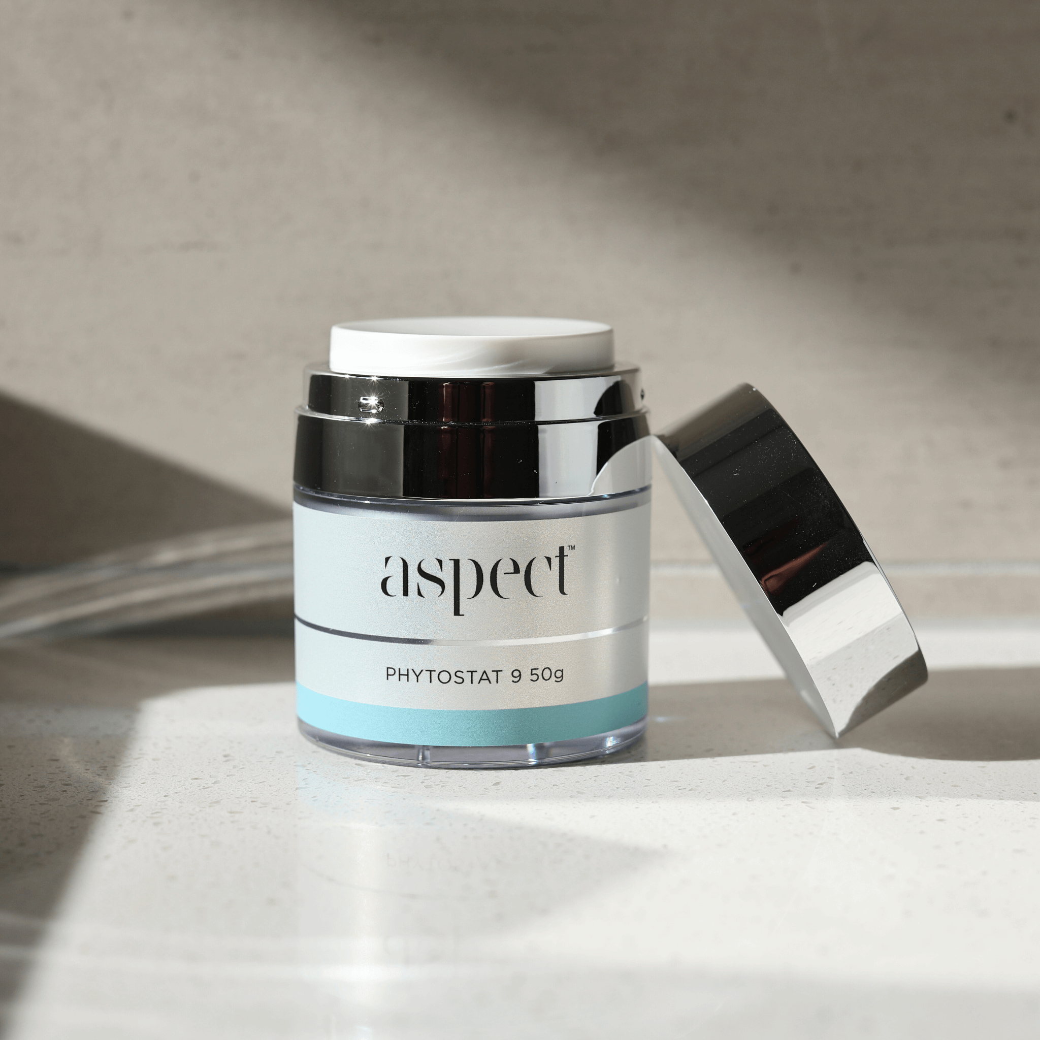 Skincare jar labeled 'aspect phytostat 9' on a neutral background