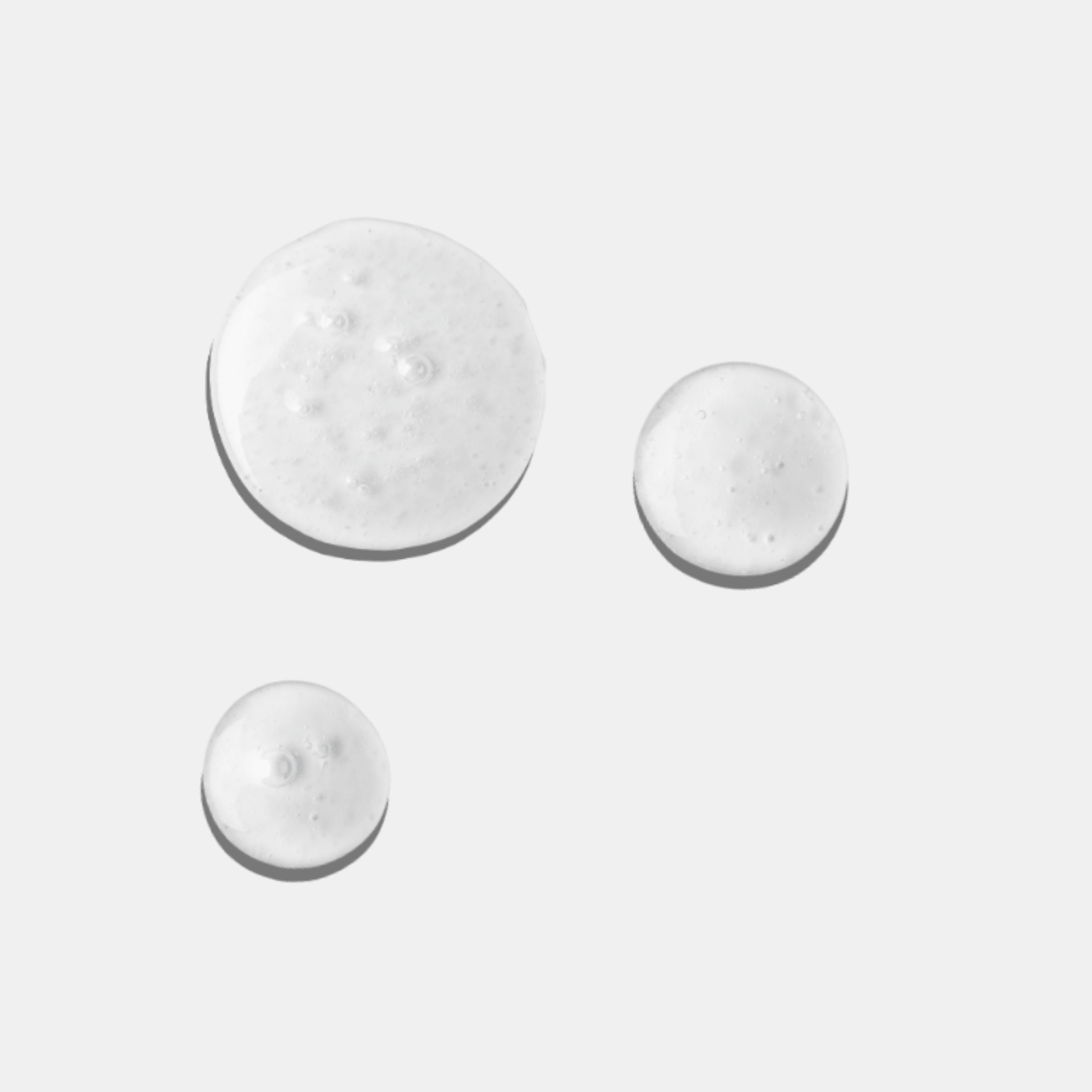 Three droplets of a white cream from Aspect Clear Skin Set on a light grey background