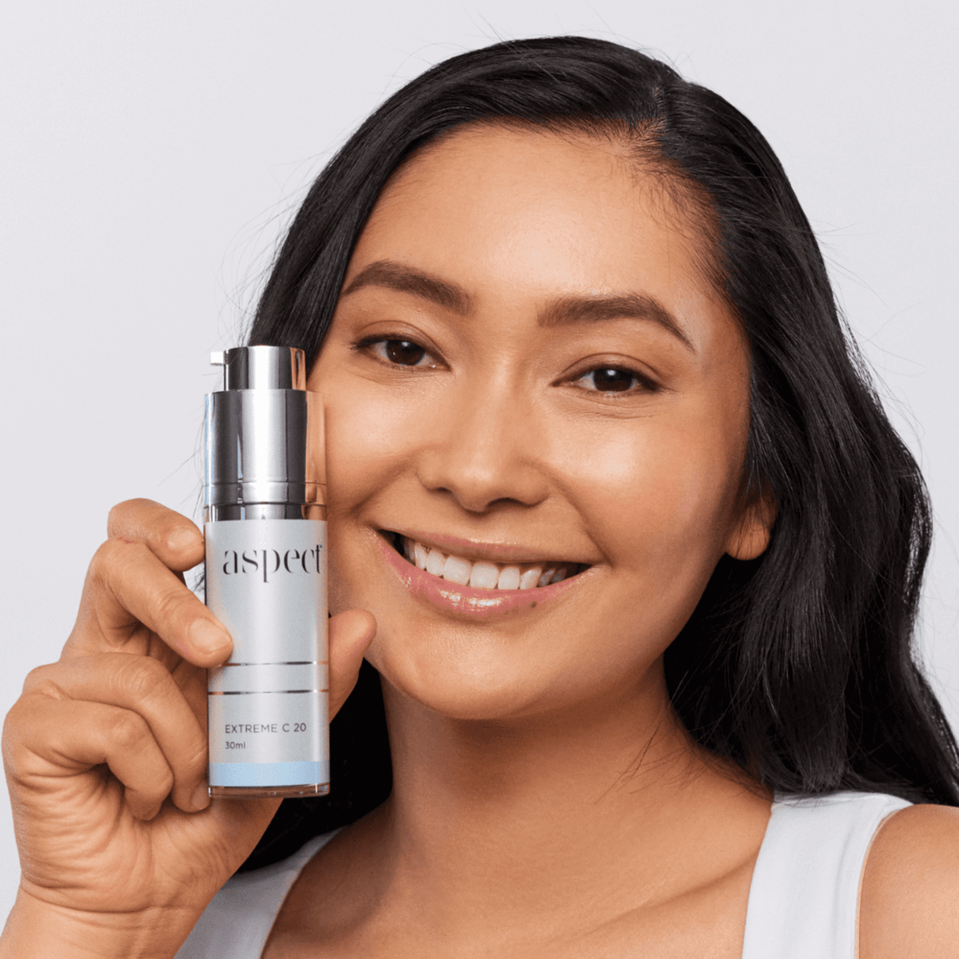 Woman holding a skincare product Aspect Extreme C 20 against a plain background