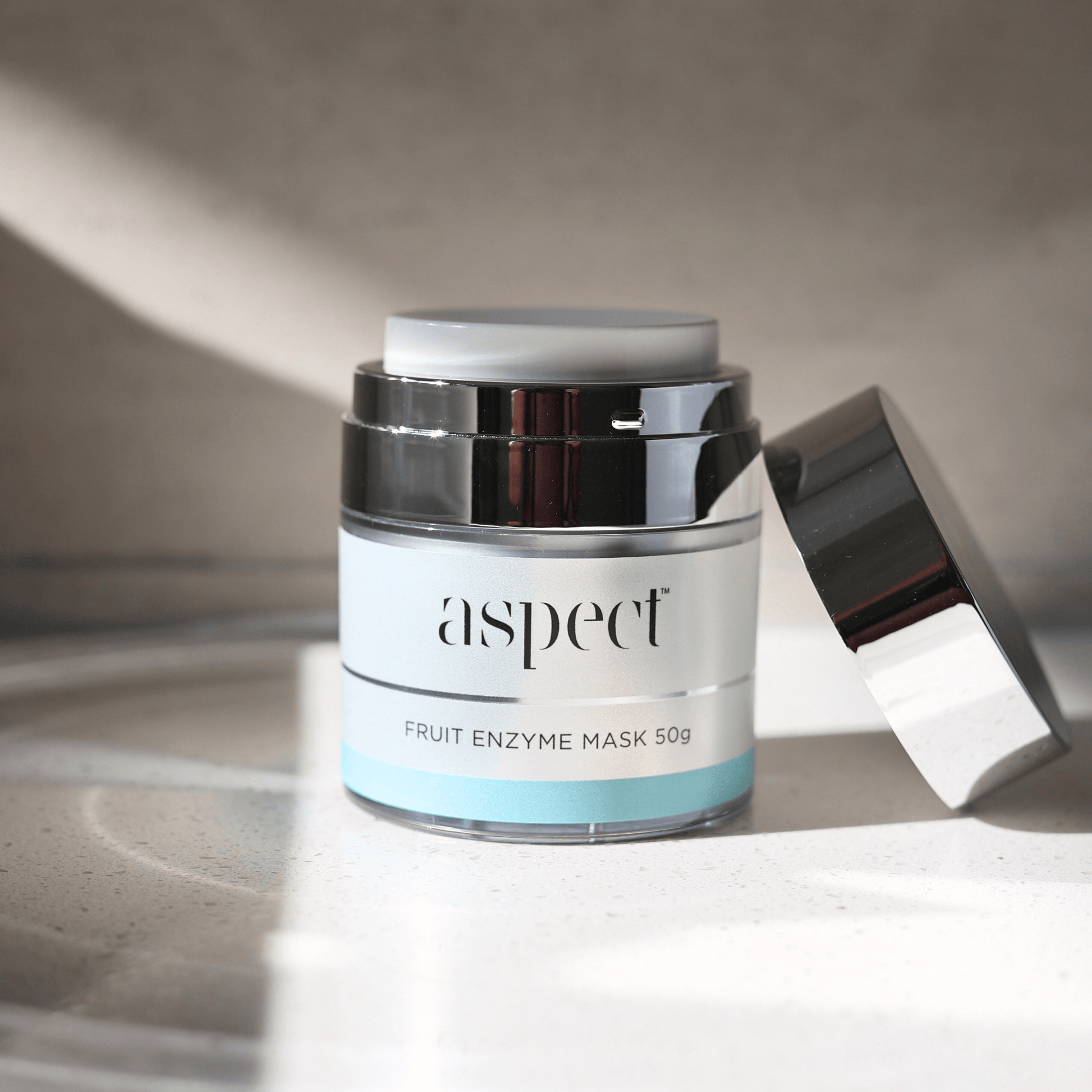 Skincare jar labeled 'aspect fruit enzyme mask 50g' on a neutral background