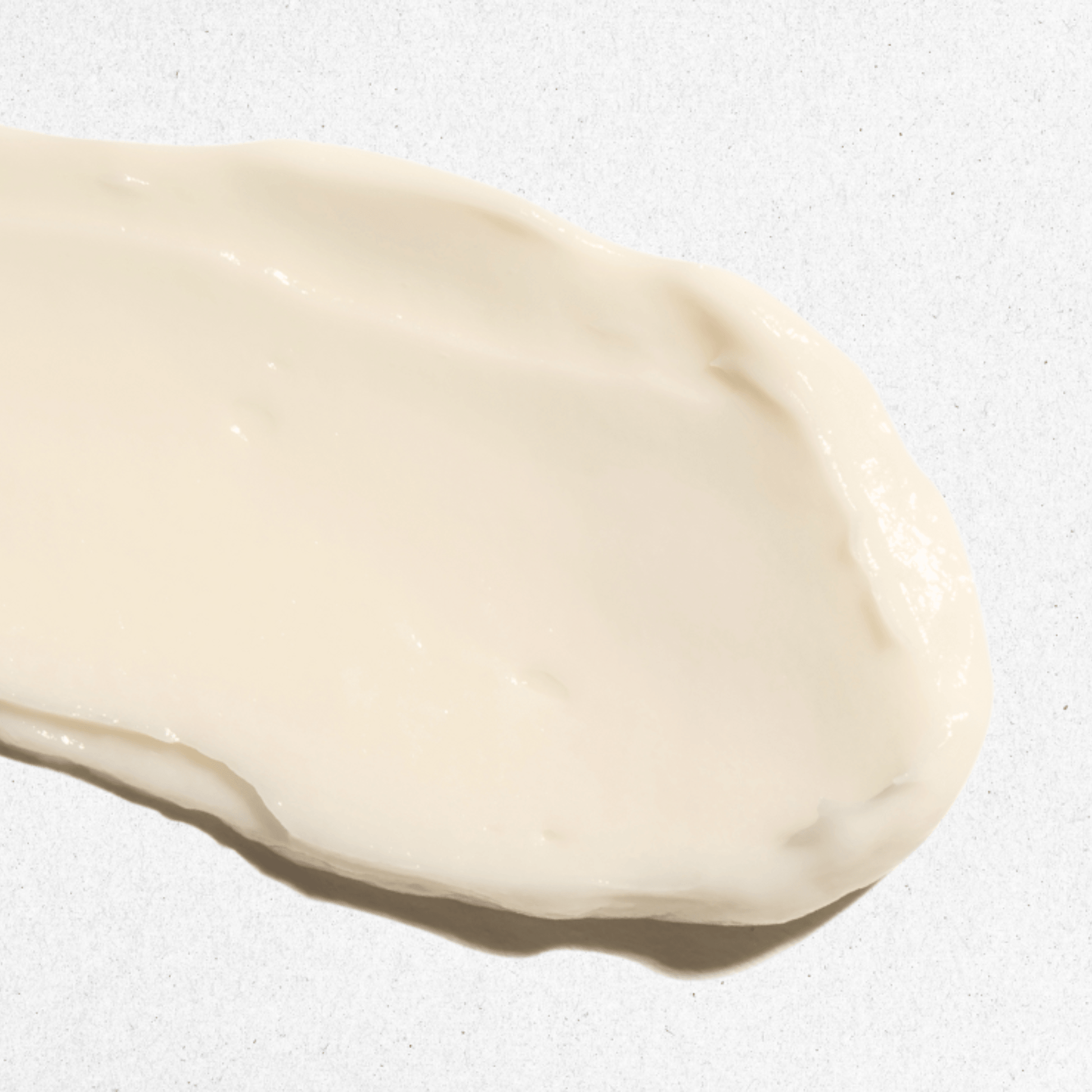Close up of Aspect Dr Nurturing Cream cleanser texture, creamy off-white cosmetic smear on a textured white background.