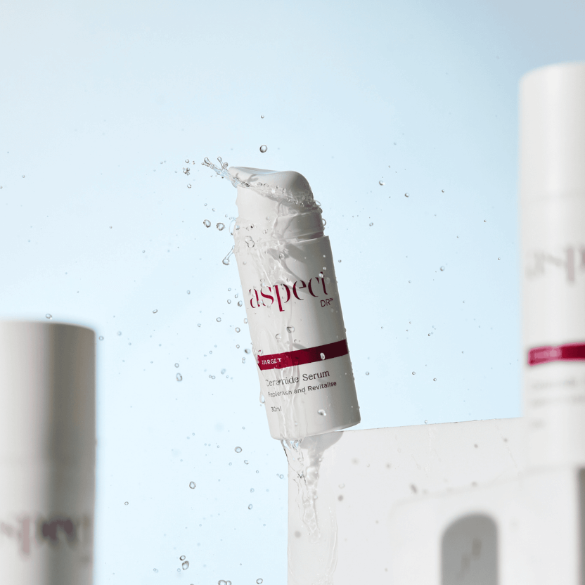 Skincare serum bottle labeled 'aspect' with water droplets on a light blue background