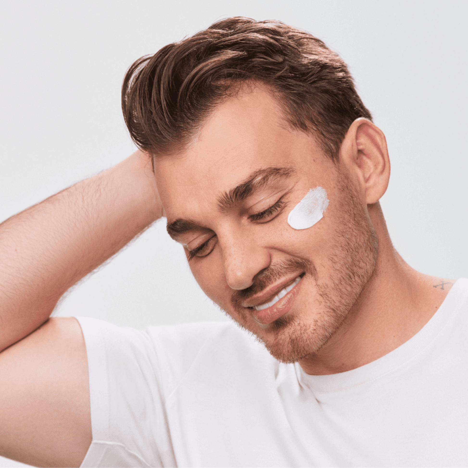 Man applying Aspect Hydra Shield cream to his face with a neutral background