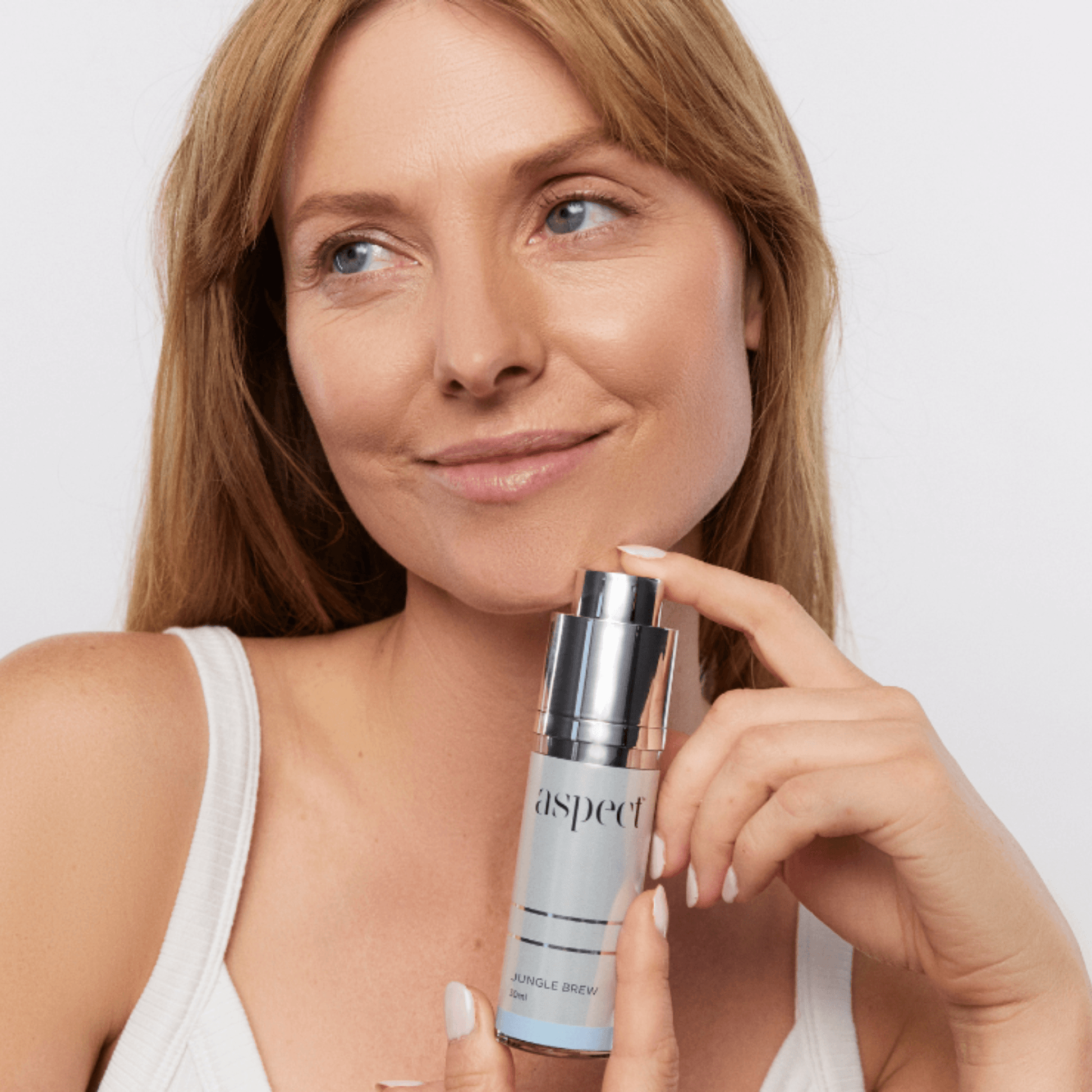 Woman holding an aspect Jungle brew serum bottle on a plain background