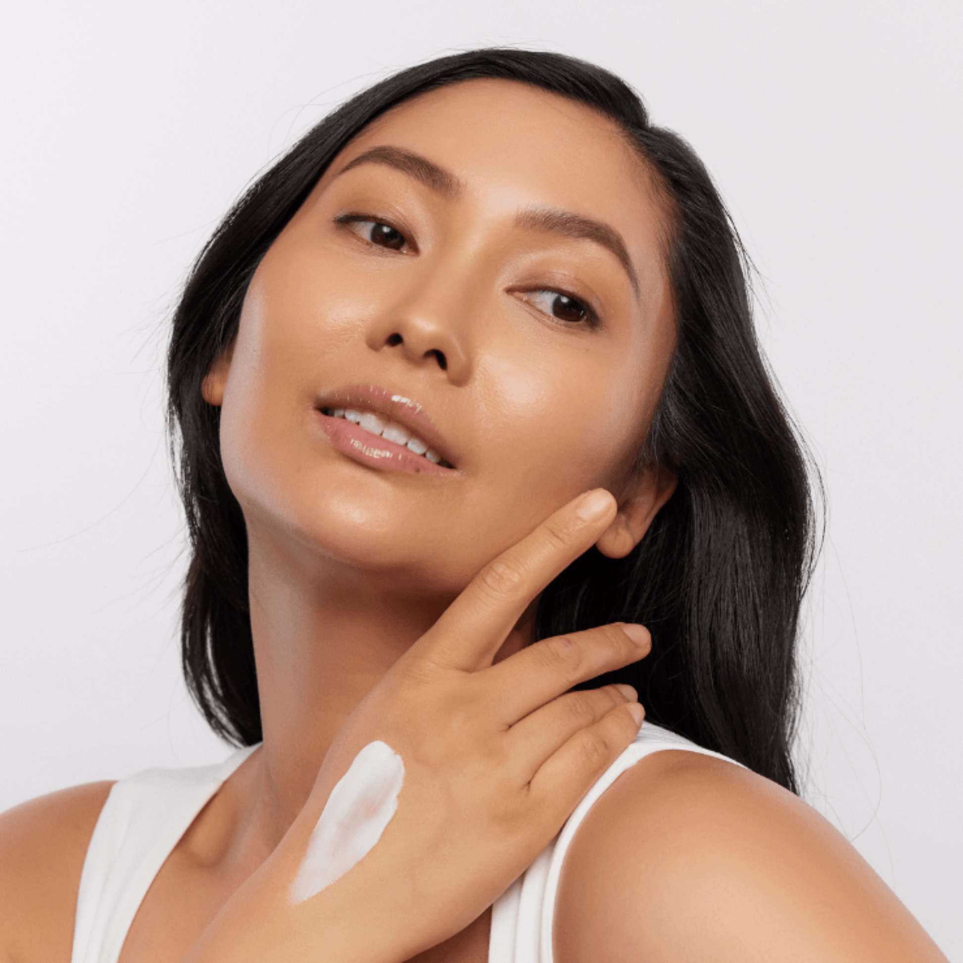 Woman applying Aspect Body Cream moisturiser to her arm with a white background