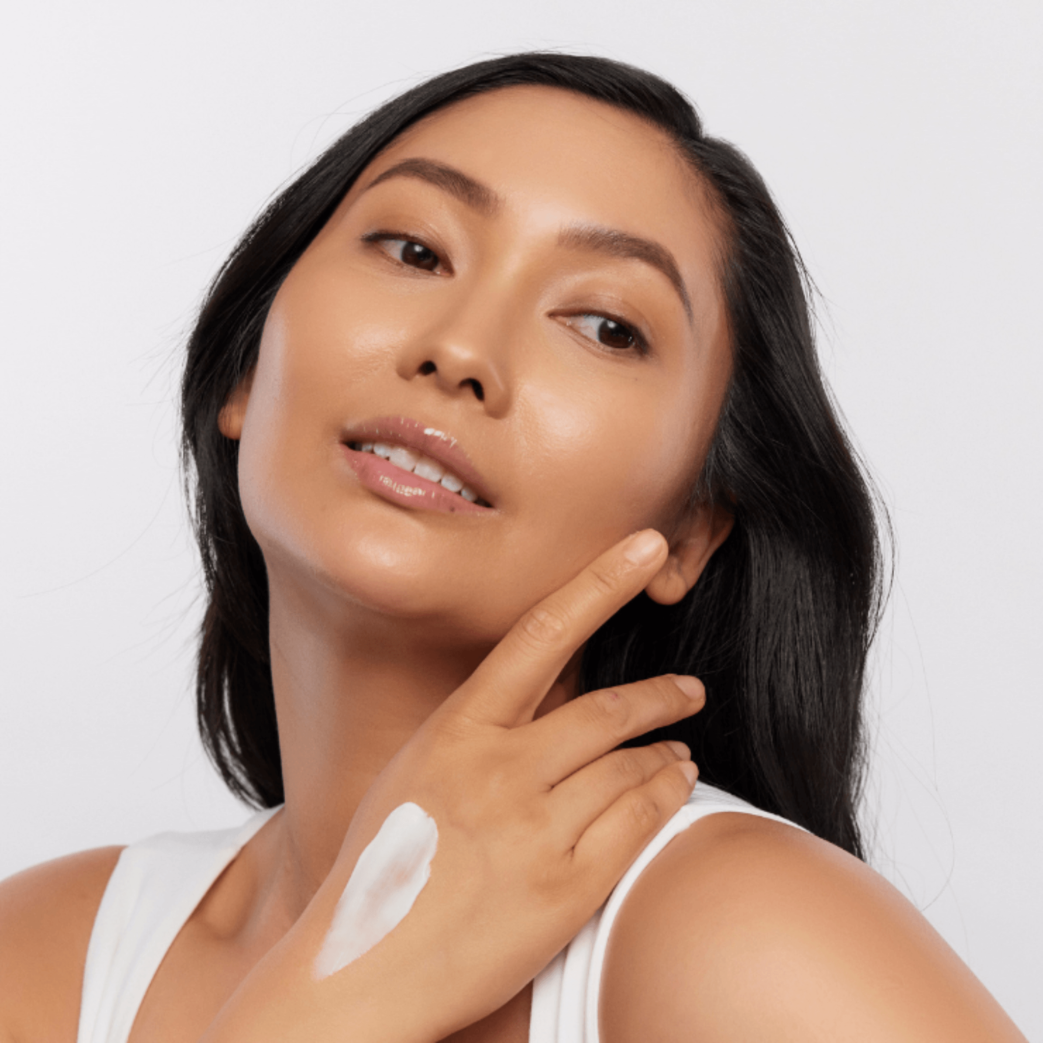 Woman applying Aspect Body Cream moisturiser to her arm with a white background