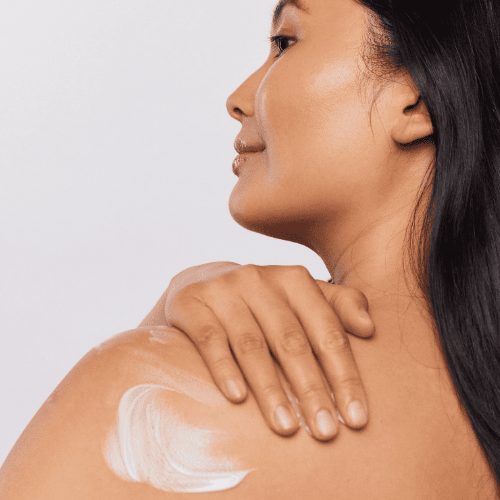 Woman applying Aspect body moisturising cream to her shoulder on a light background