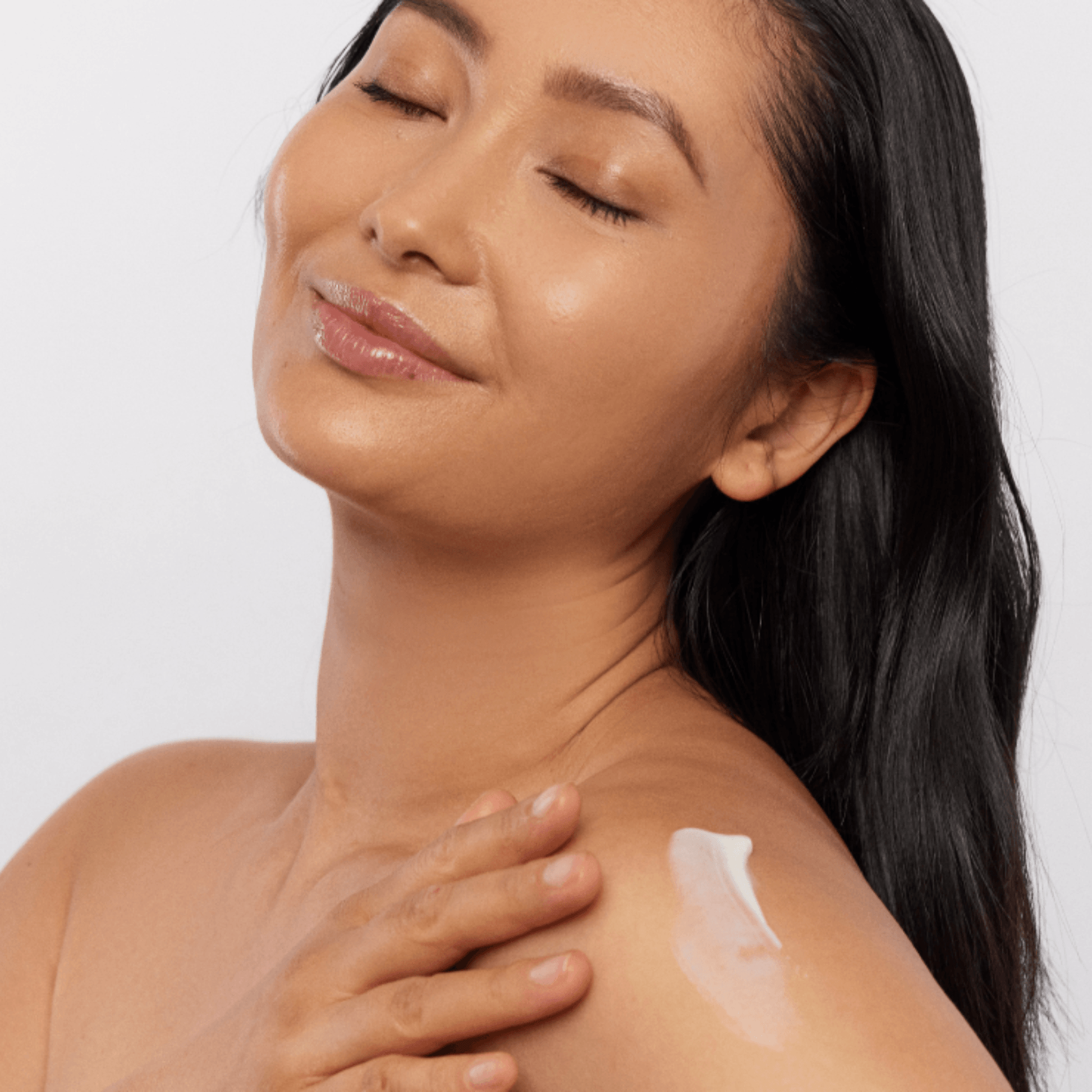 Woman applying Aspect moisturiser to her shoulder with a white background