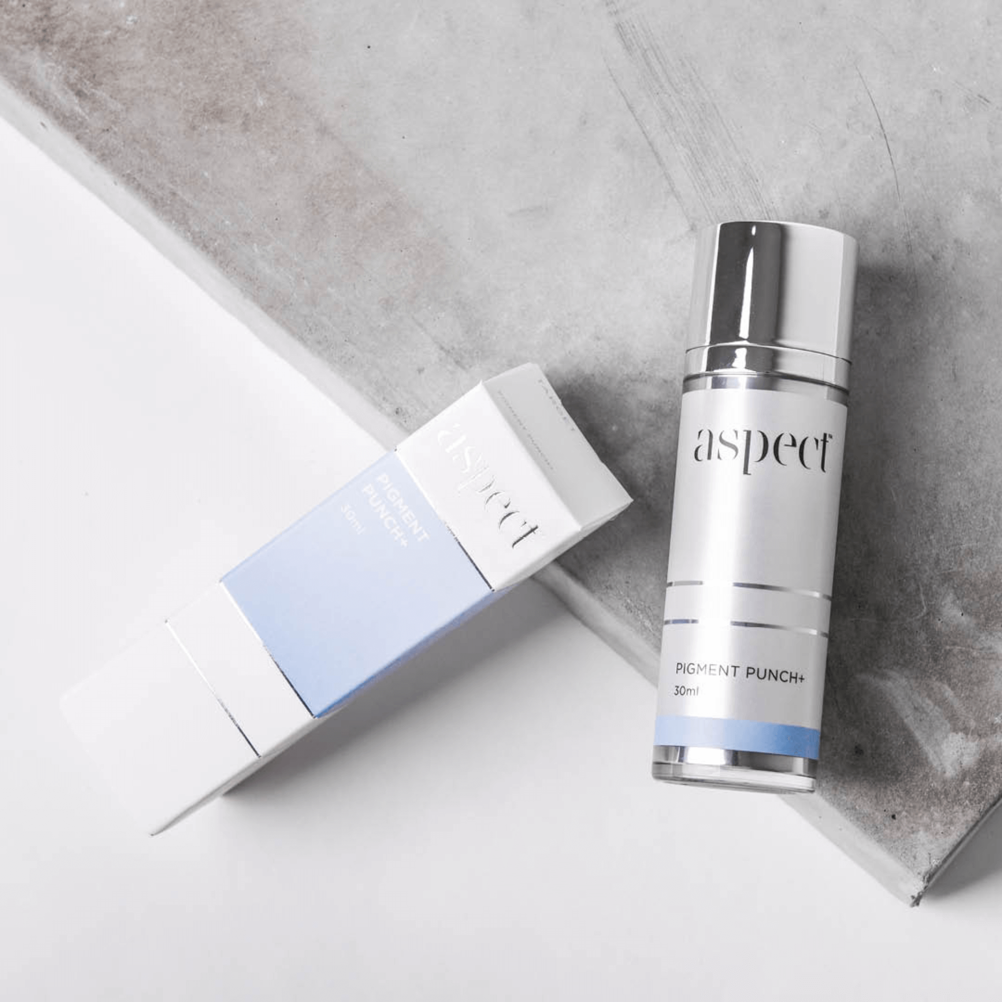 Skincare bottle labeled 'aspect' on a grey surface with packaging.