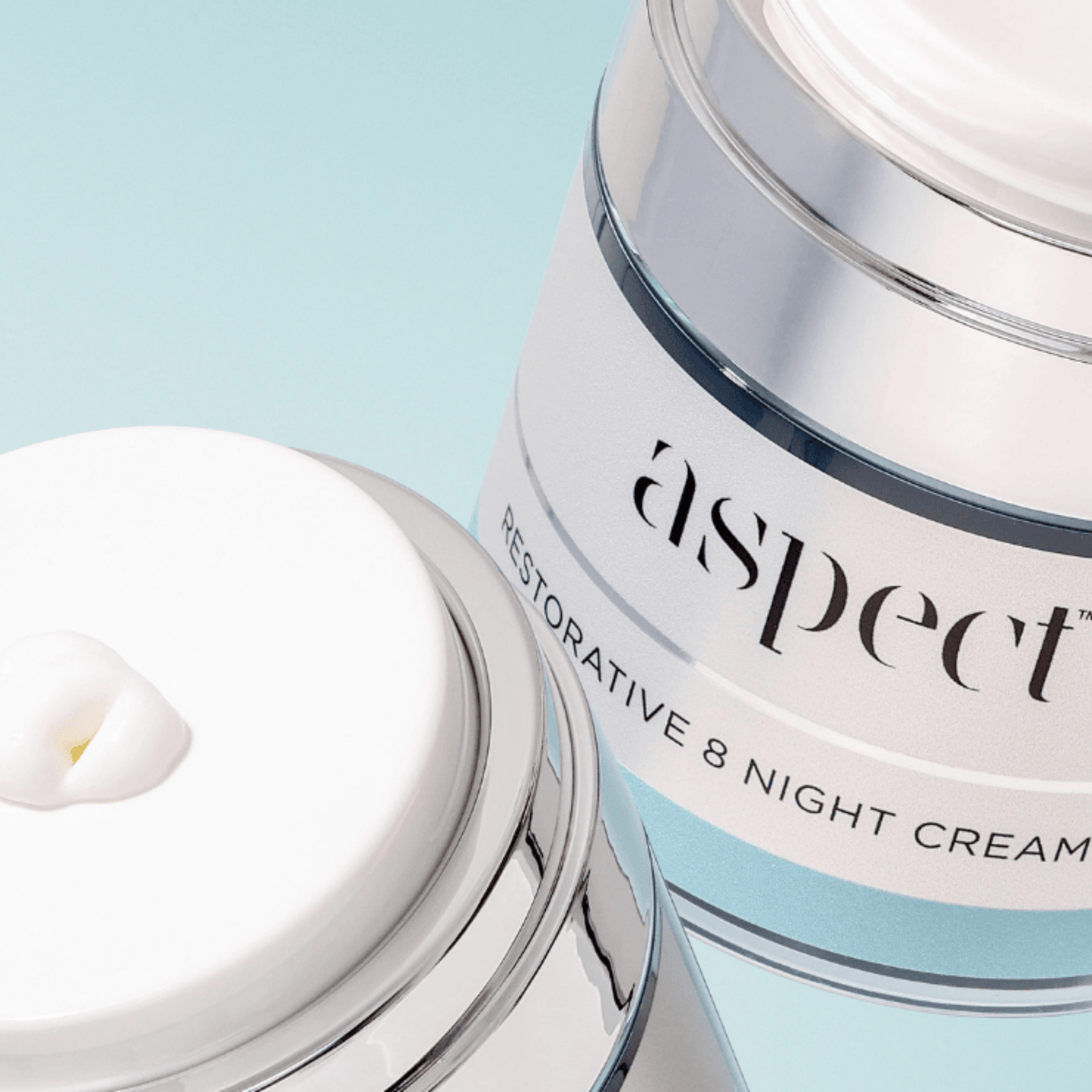 Two jars of 'aspect' restorative 8 night cream on a light blue background