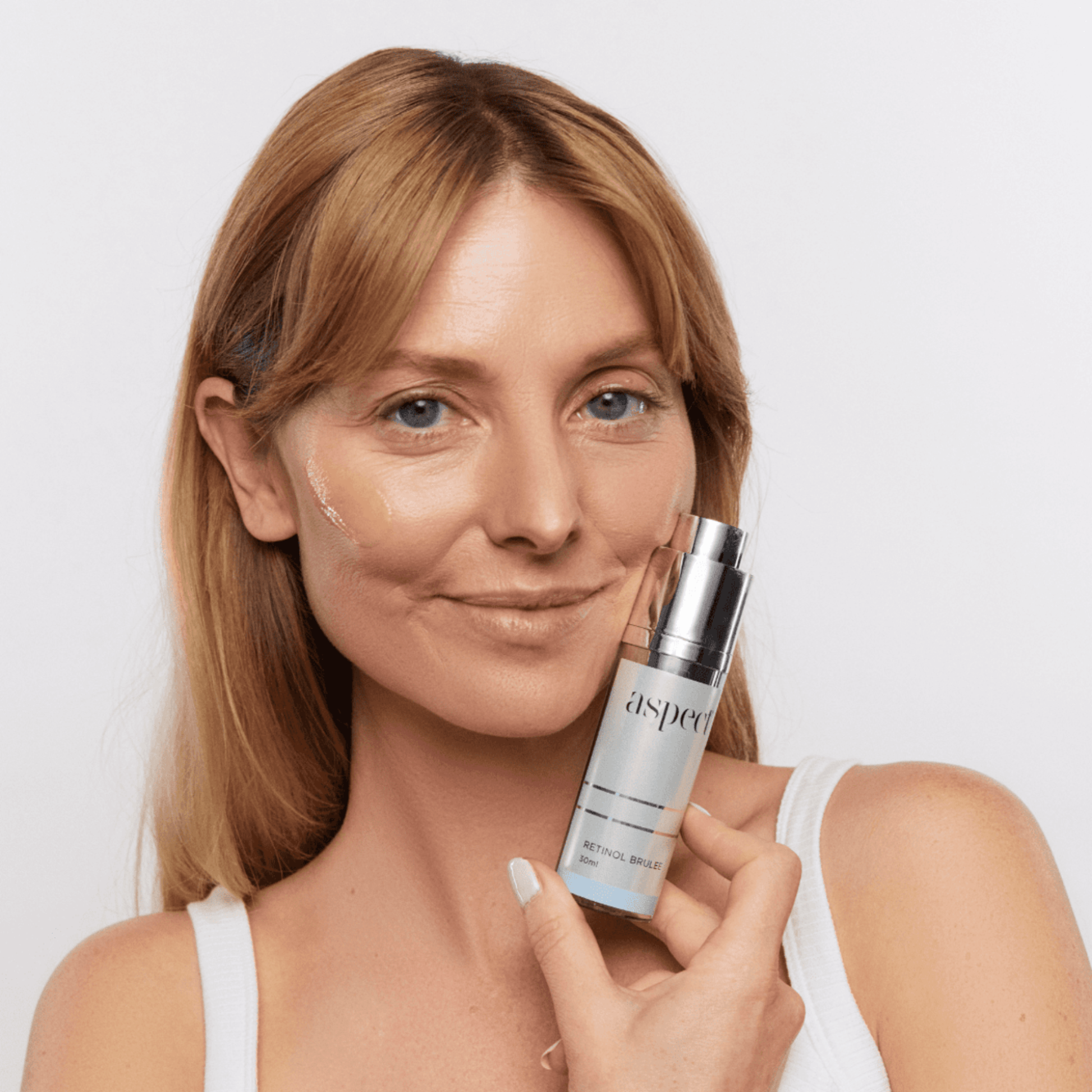 Woman holding an Aspect Brulee product with a plain background