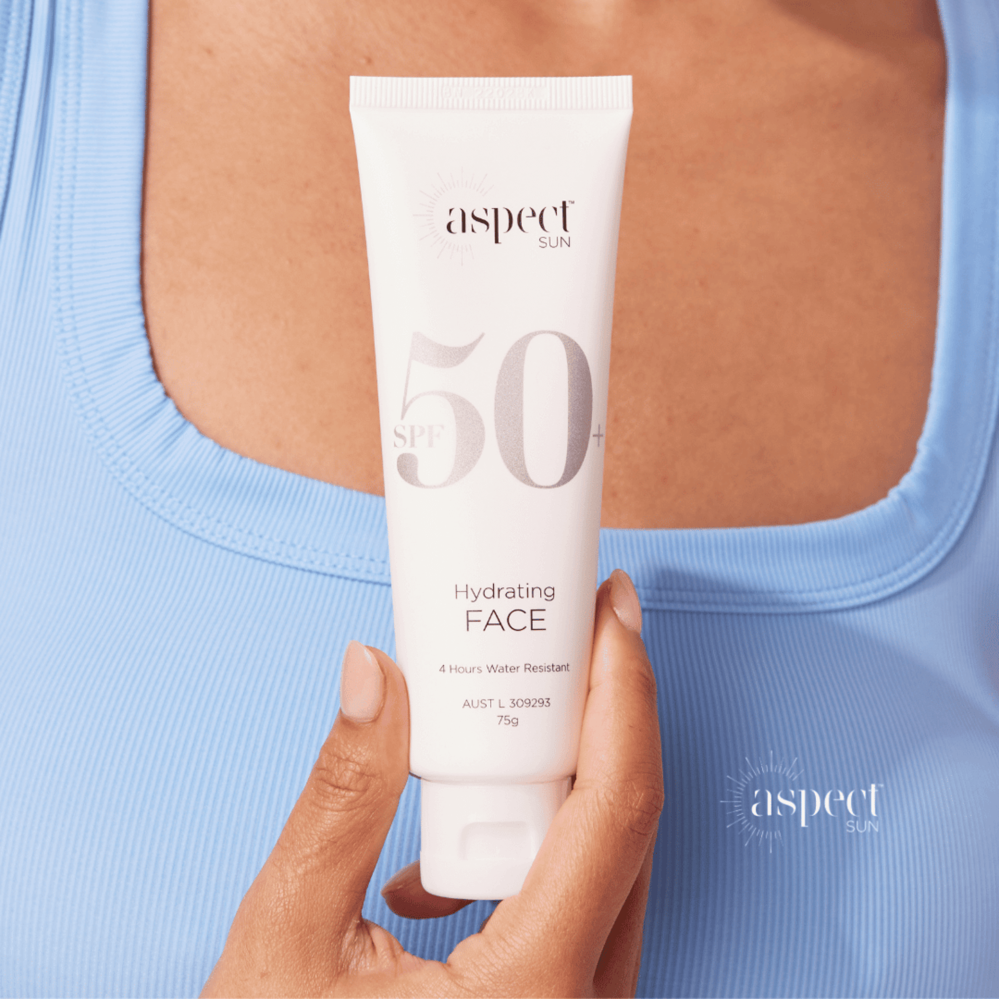 Person holding a tube of Aspect Sun SPF50 Hydrating Face cream against a blue background