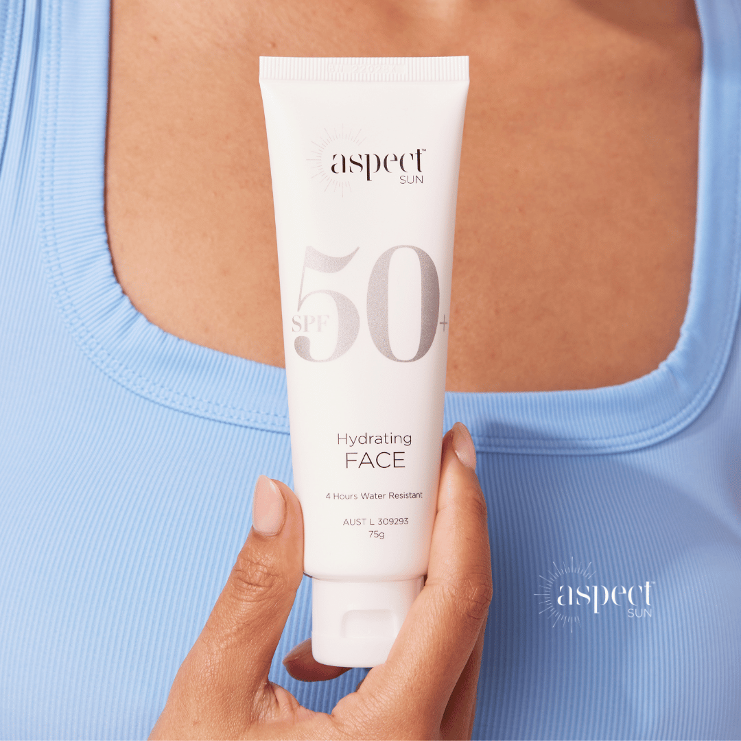 Aspect Sun Sunscreen held in hand against blue top
