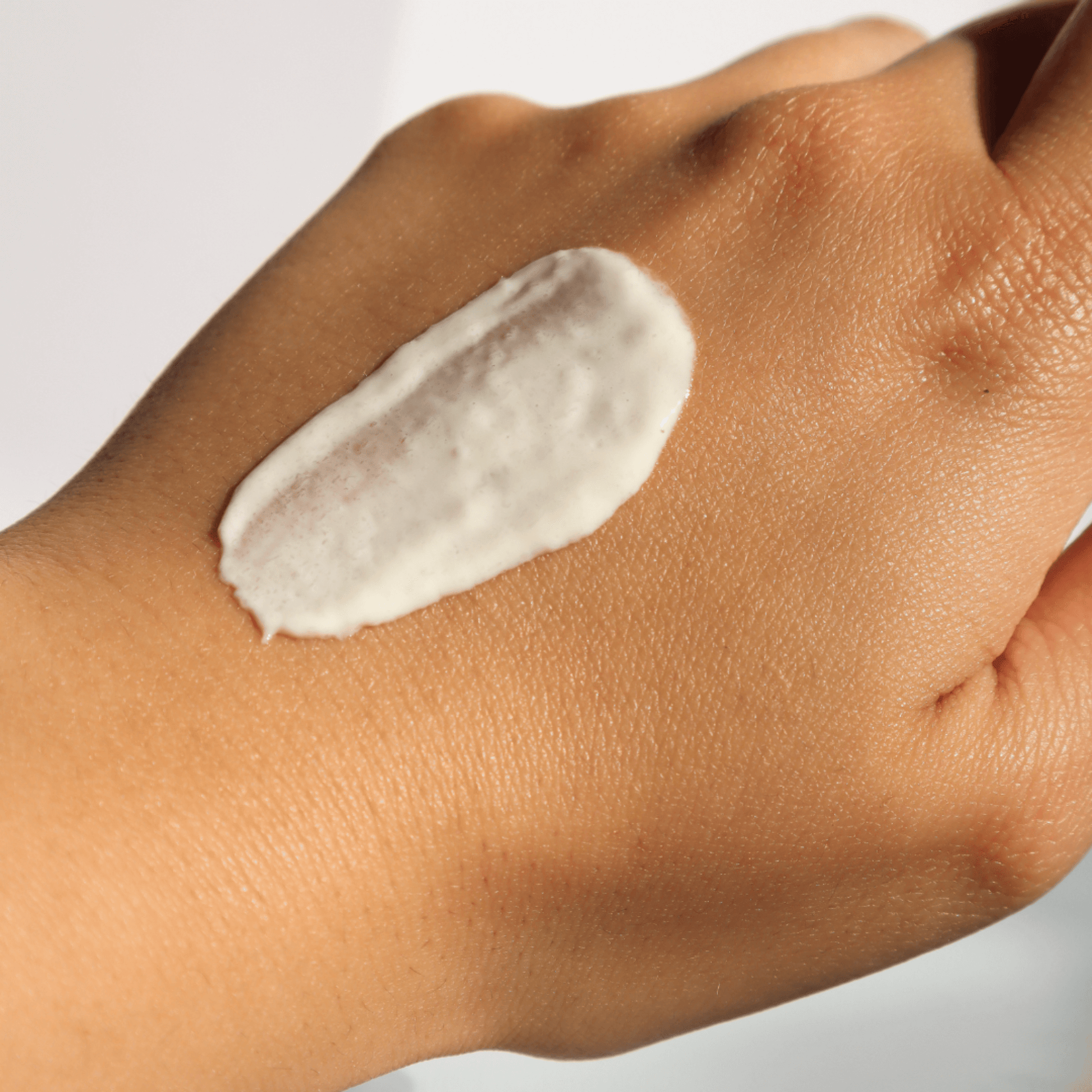 Hand with a swatch of Aspect Sunscreen cream on a neutral background