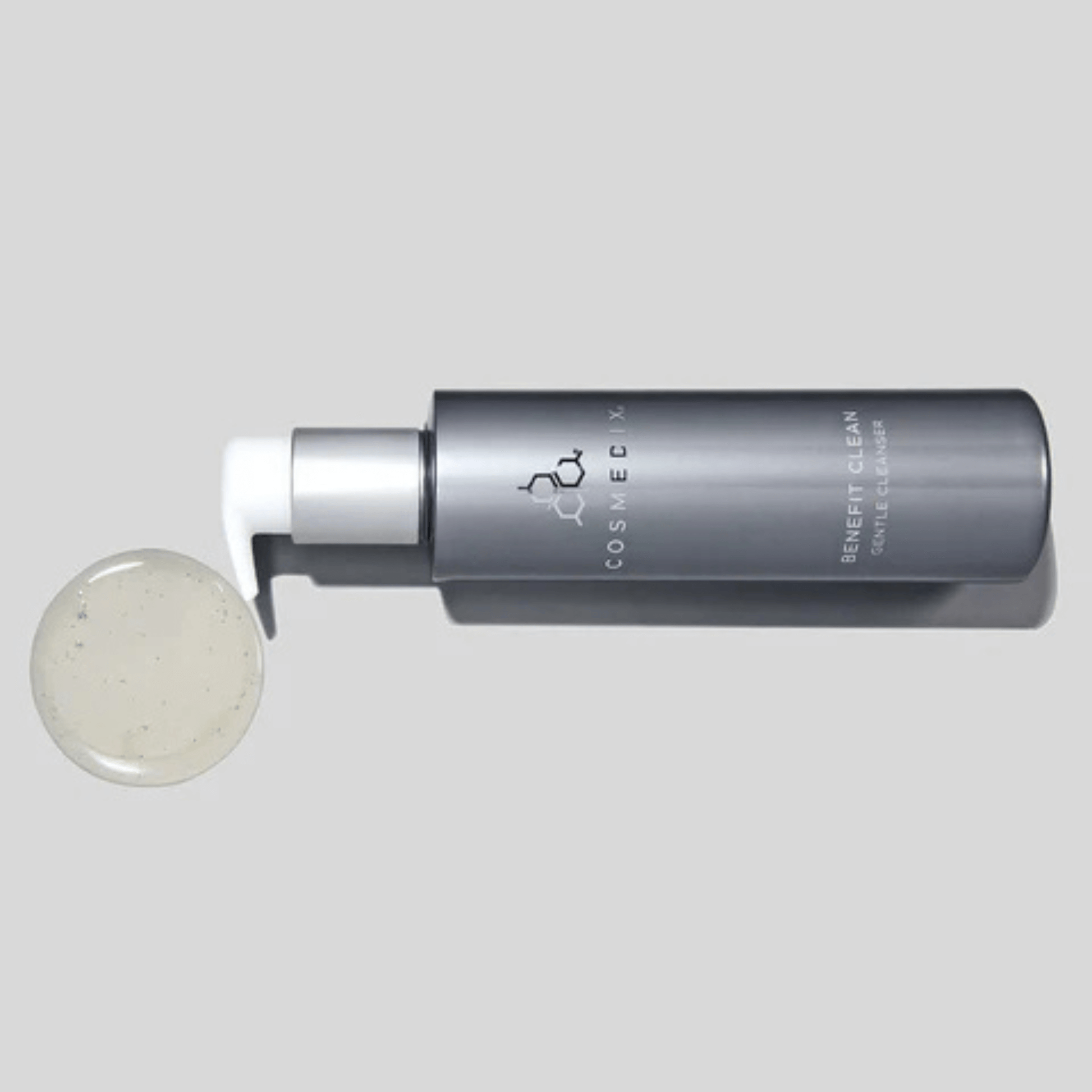 Cosmedix benefit clean cleanser tipped over with small amount of cleanser on a light grey background