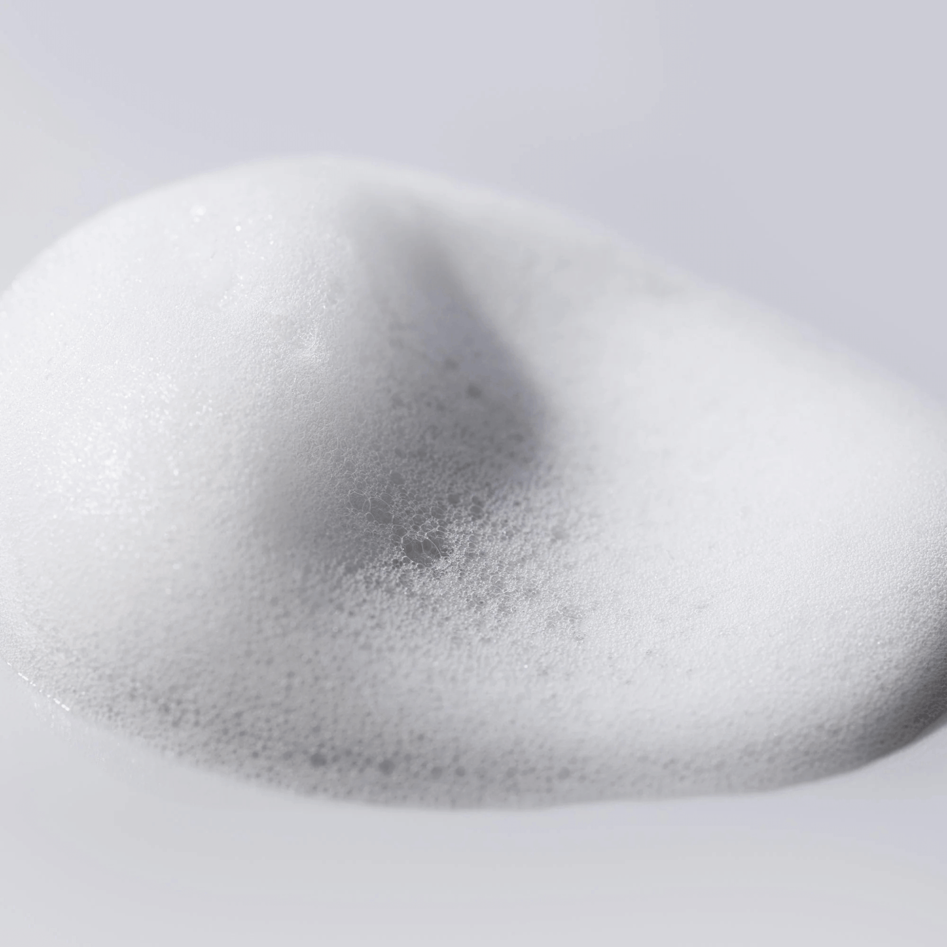 Close-up of Cosmedix Clarify Foaming cleanser droplet on a grey background