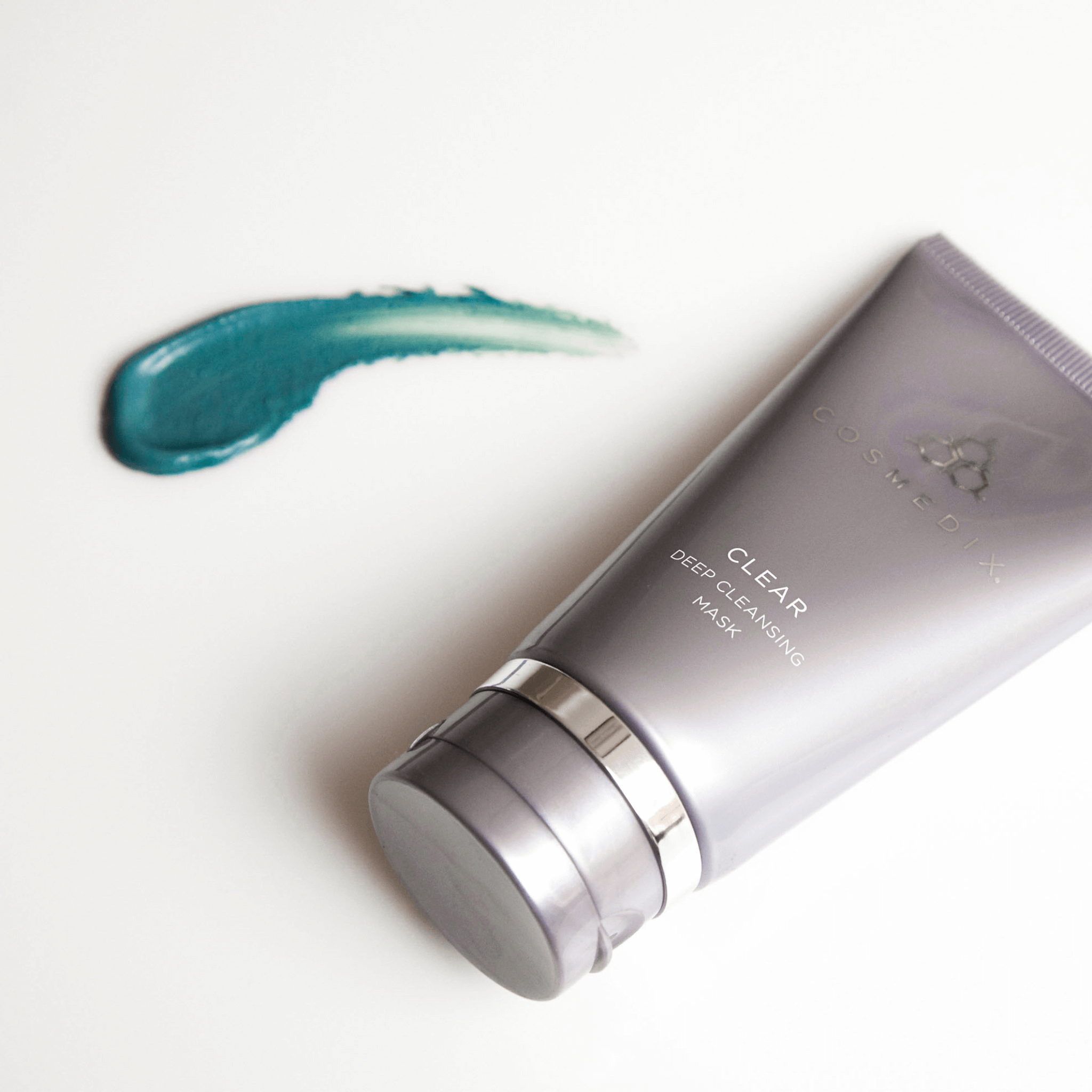 Cosmedix Clear mask with a swatch of green cream on a light background