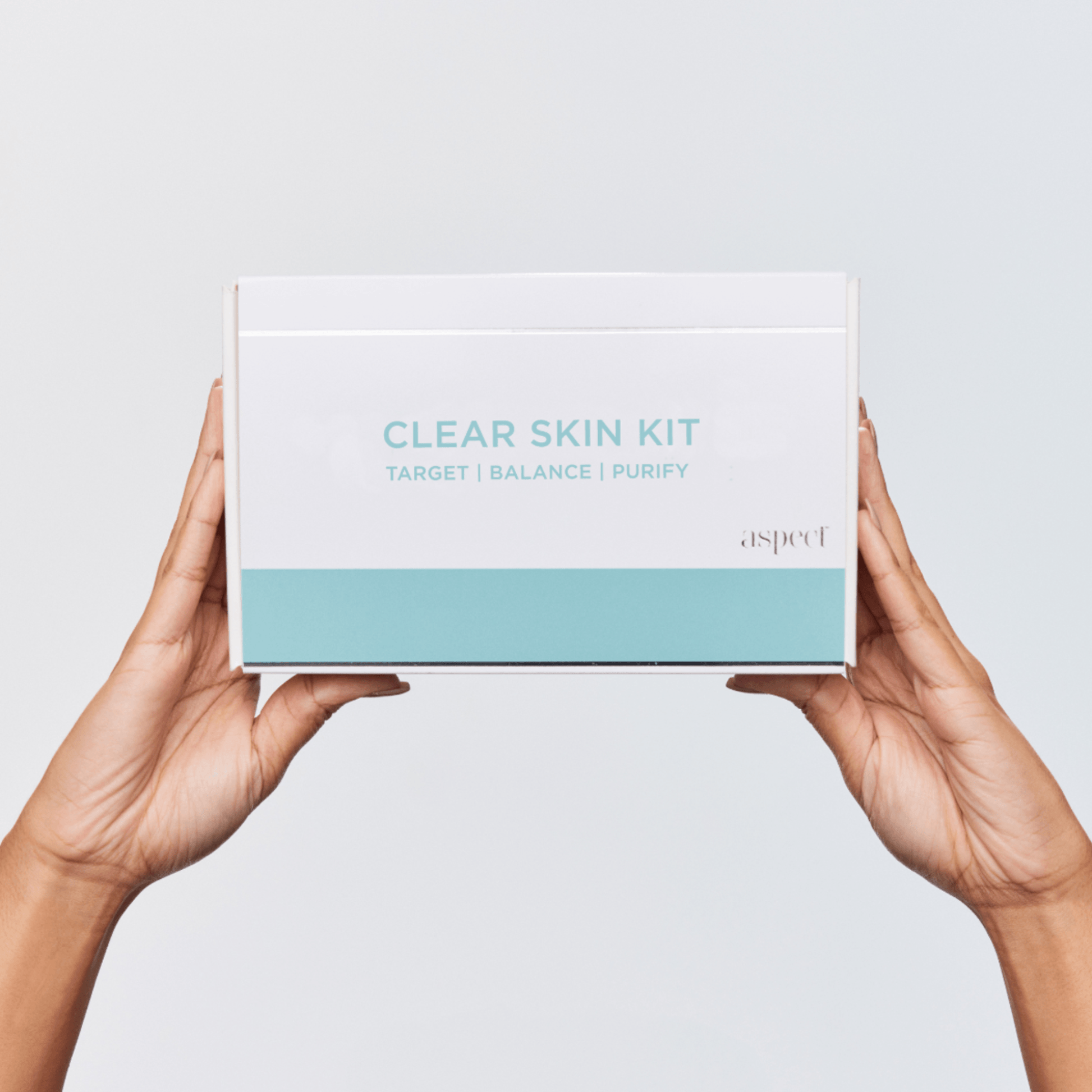 Aspect Clear Skin Kit box held by hands against a light grey background
