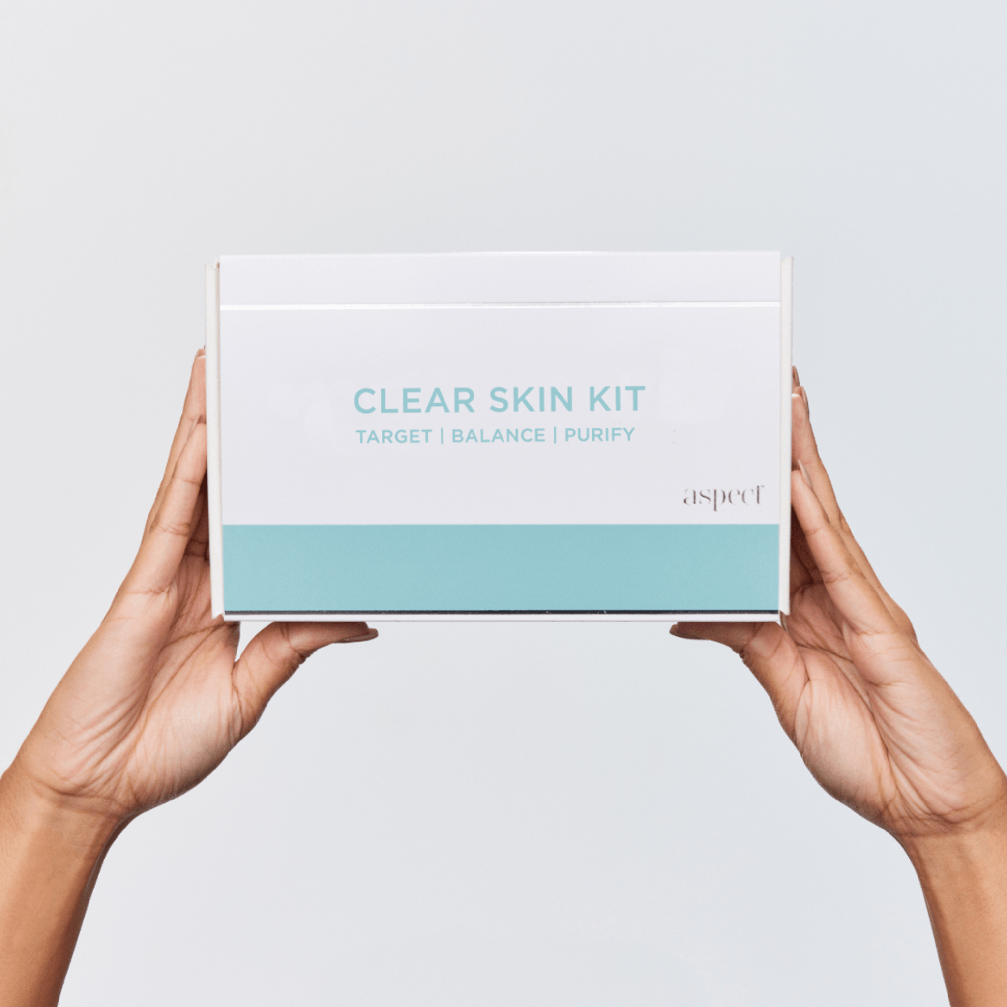 Aspect Clear Skin Kit box held by hands against a light grey background
