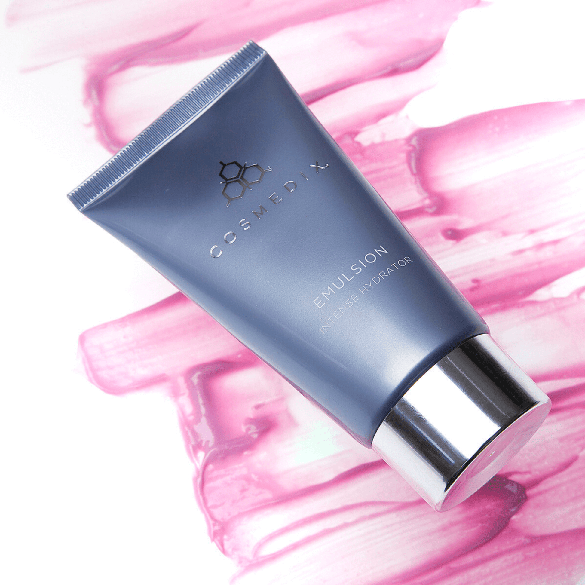 Cosmedix emulsion tube on a pink moisturiser swatch and white abstract background