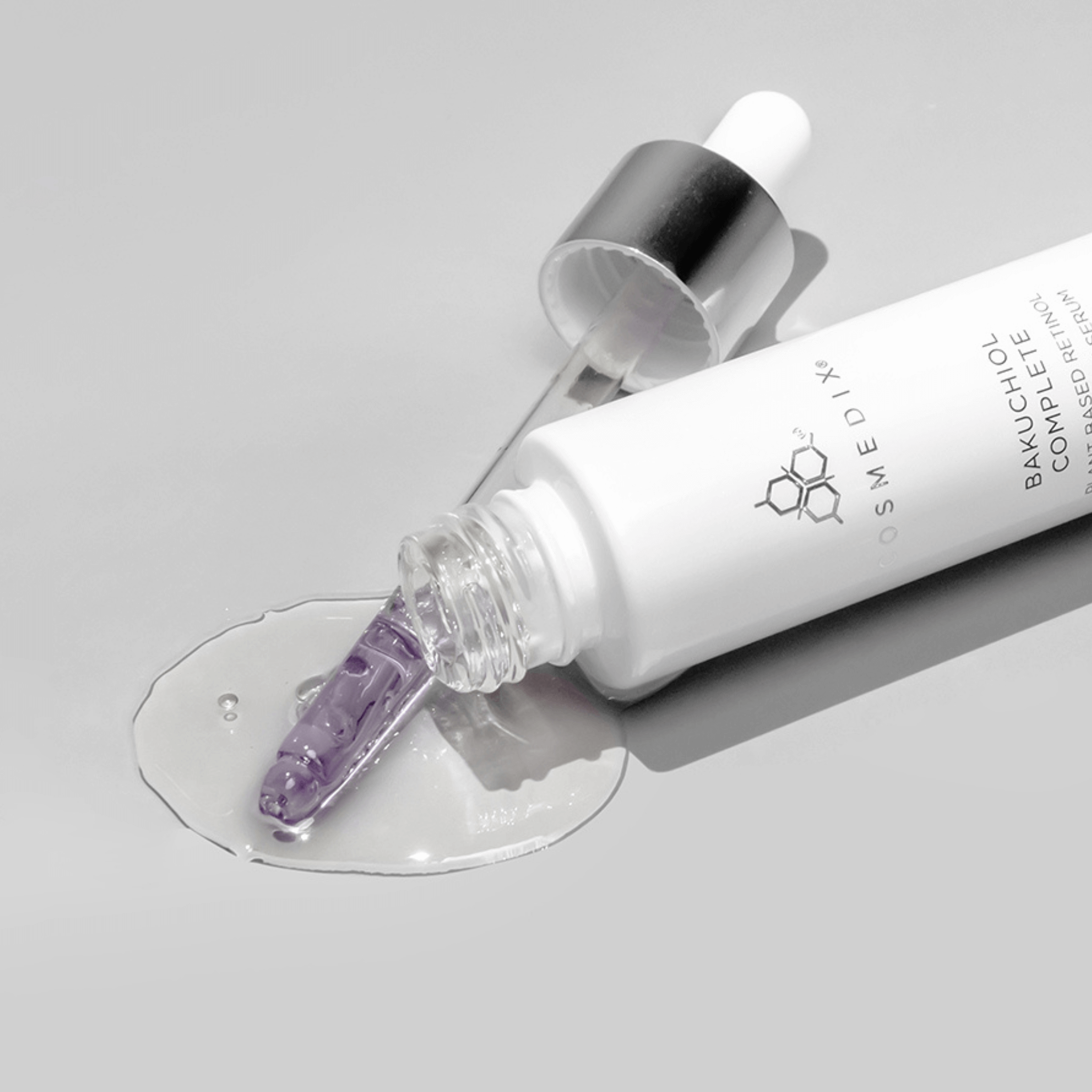 Cosmedix Bakuchiol dropper with purple liquid and white bottle on a grey background