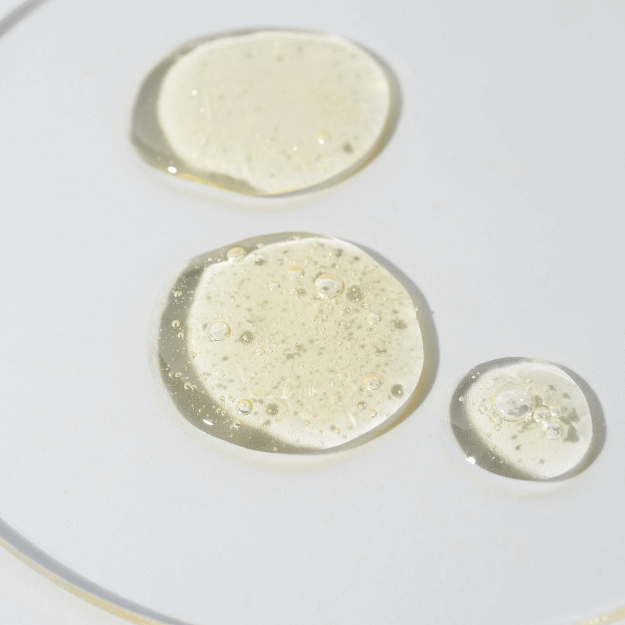 Three small droplets of benefit clean cleanser on a white background