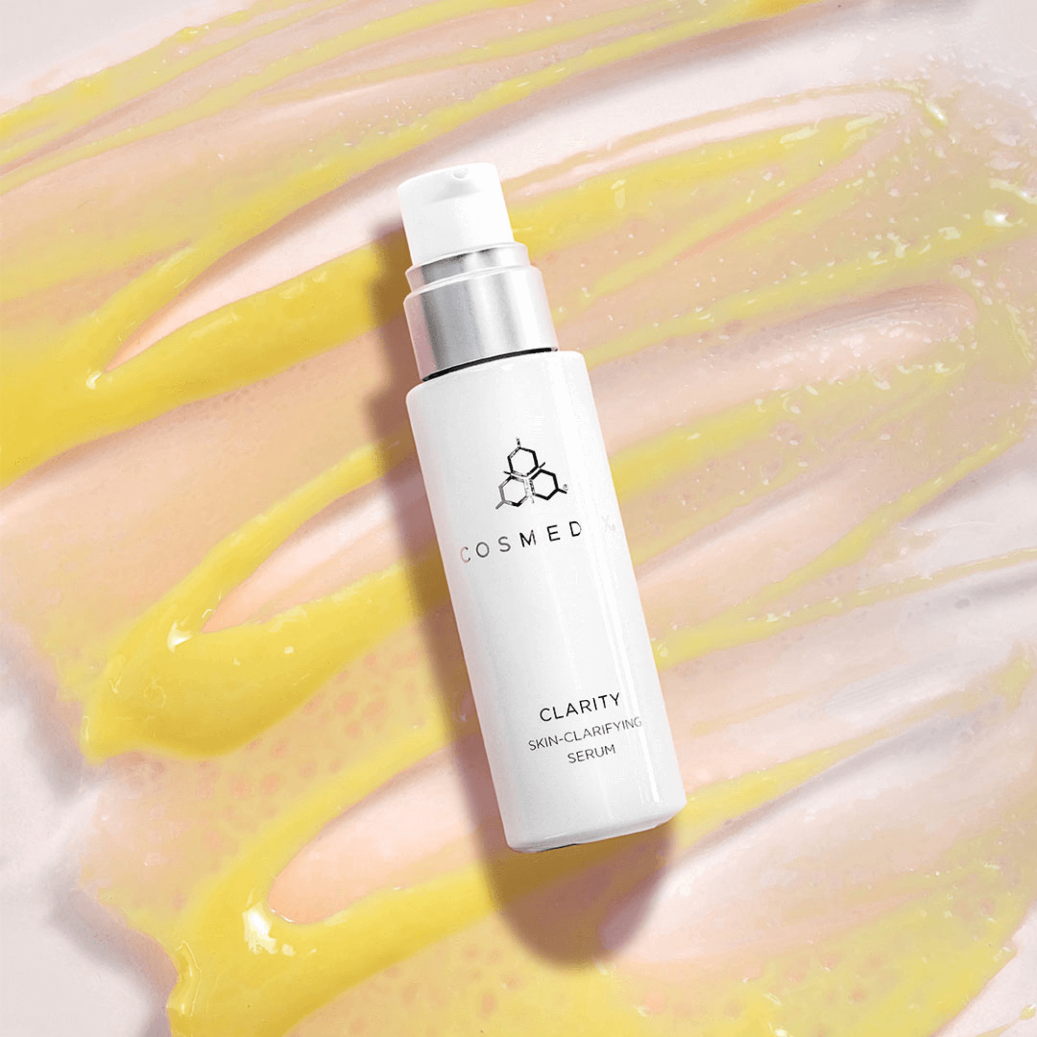 Cosmedix Clarity serum bottle on textured yellow serum on pink background