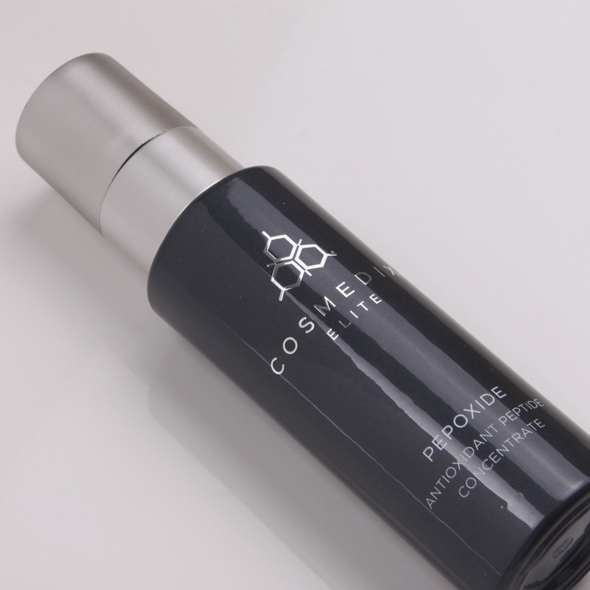 COSMEDIX ELITE Pepoxide serum bottle laying flat on a light grey background