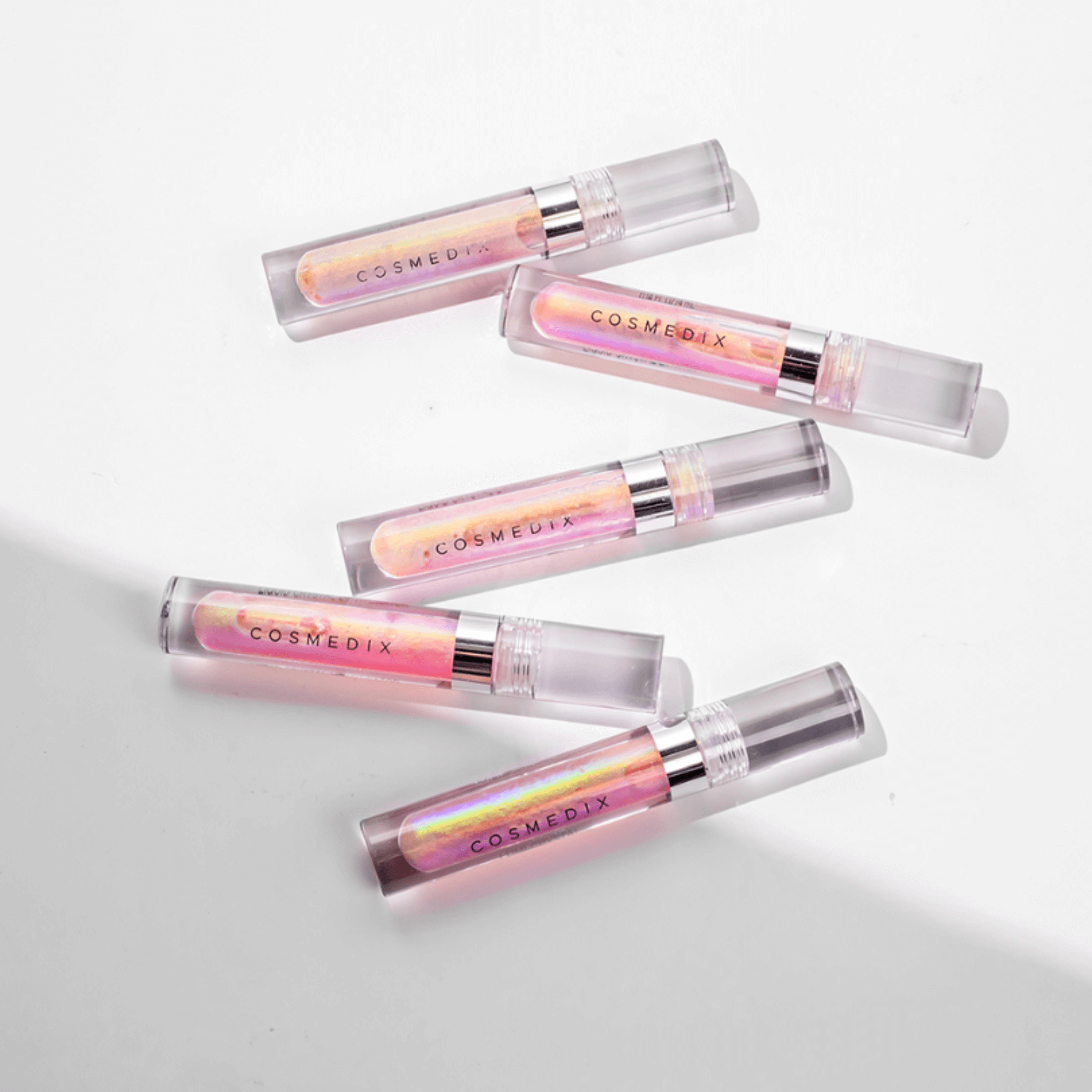 Five Cosmedix lip glosses on a light grey background