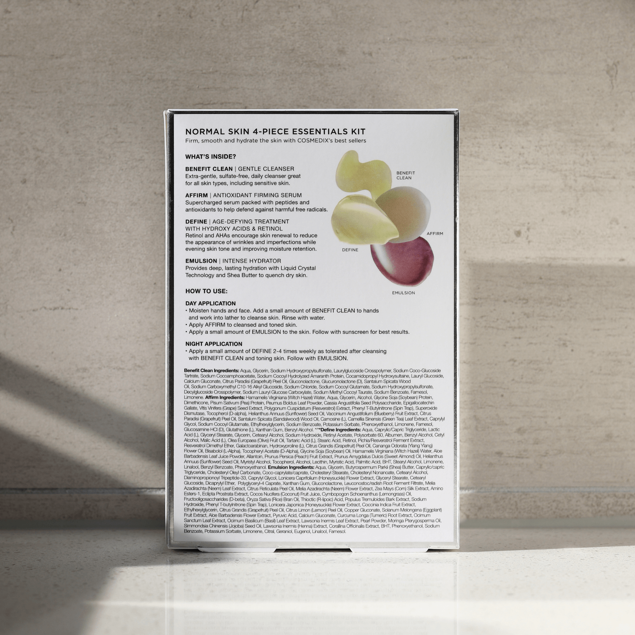 Back of box for Cosmedix normal skin 4-piece essentials kit on a textured wall background