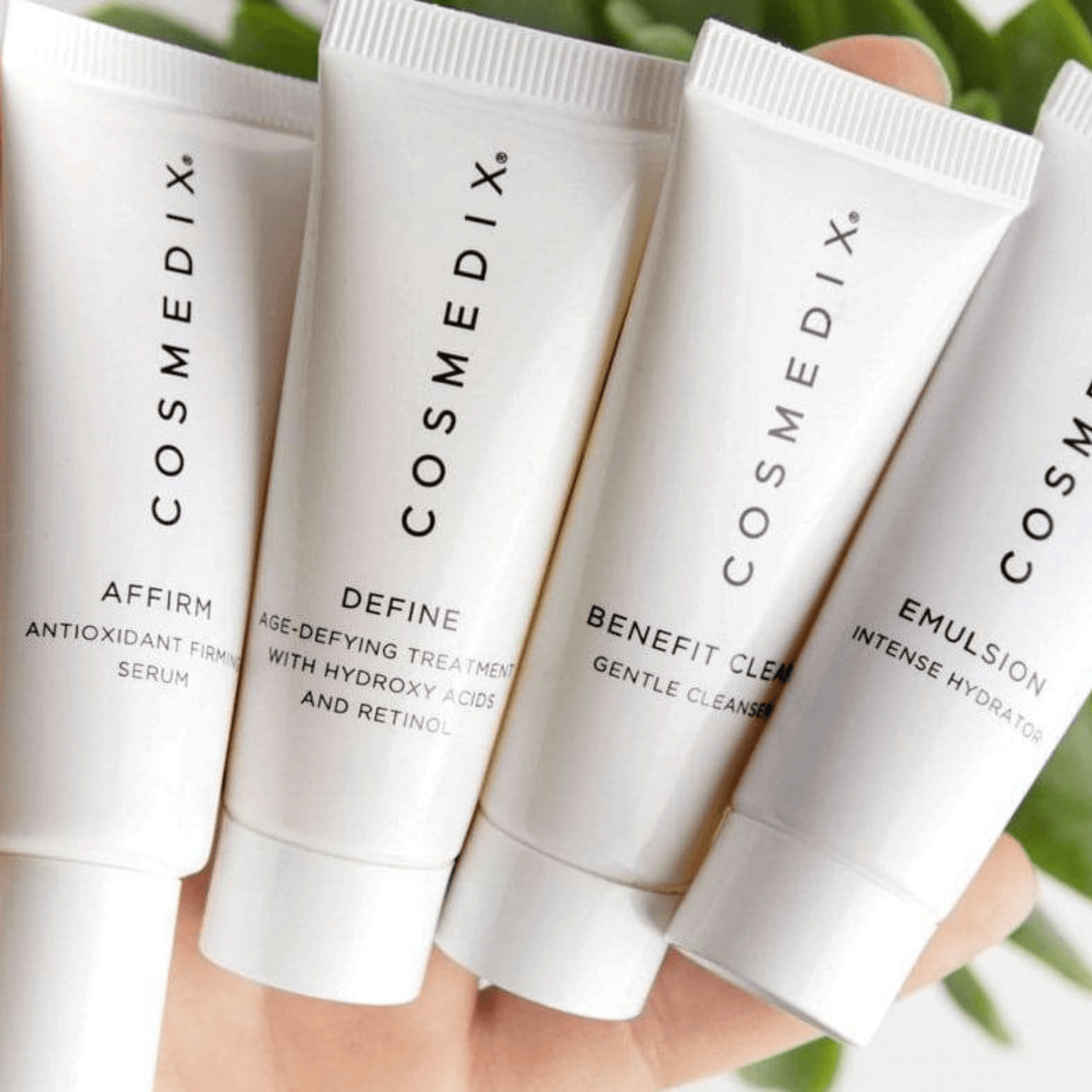 Four Cosmedix skincare product tubes held together with a blurred green background
