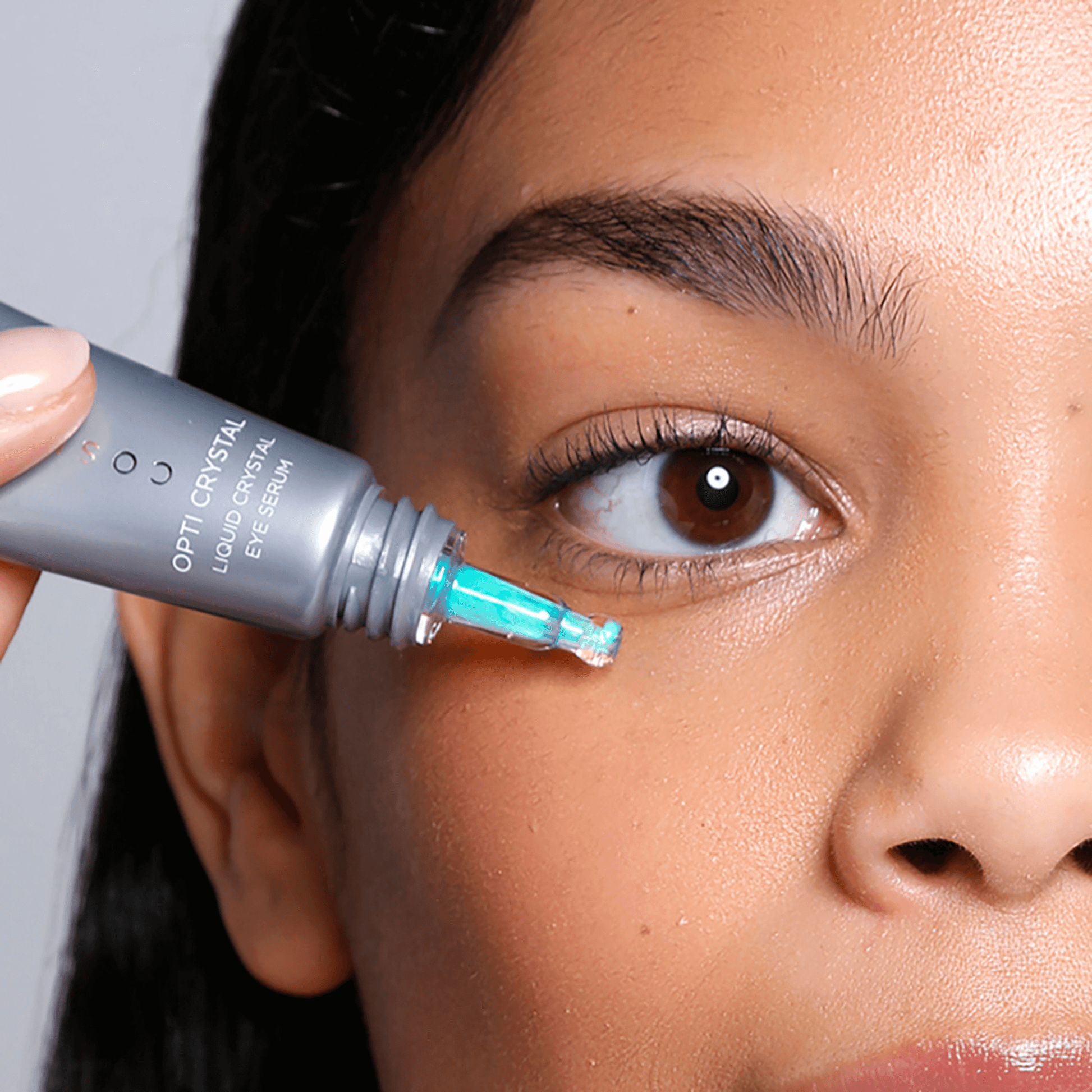 Person applying Opti-Crystal liquid eye serum to their undereye