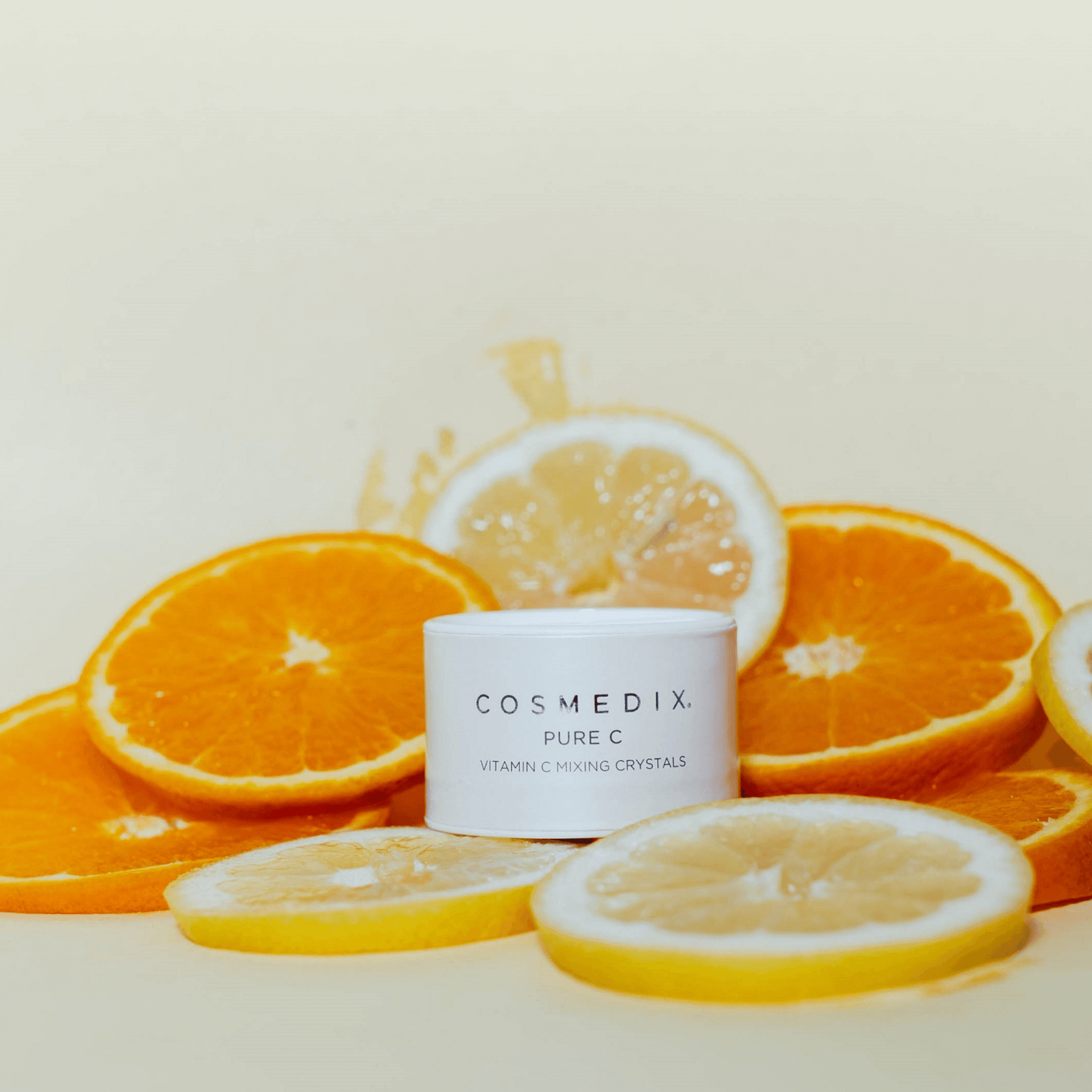 Cosmedix Pure C product with sliced oranges and lemons on a beige background