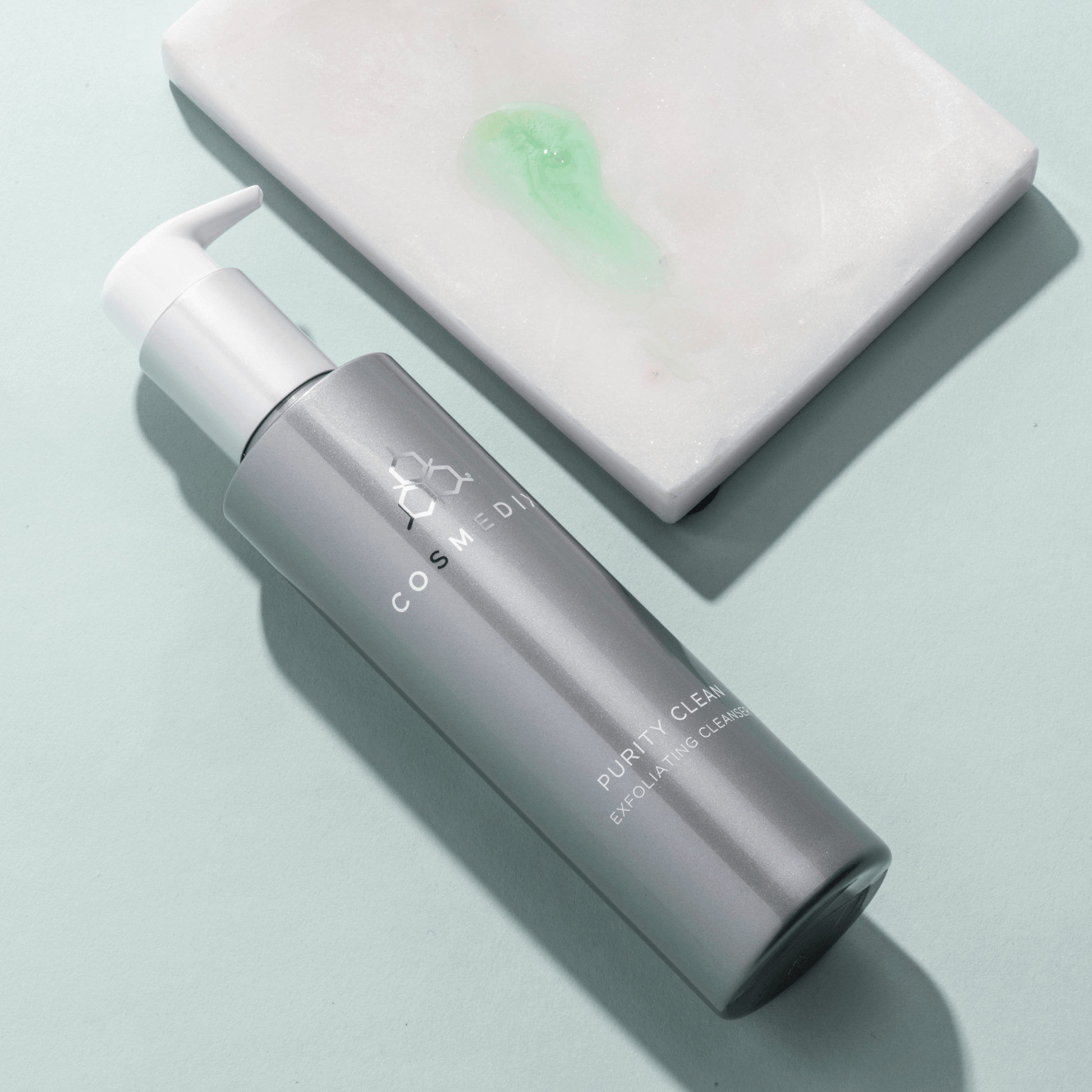 Cosmedix purity clean cleanser bottle with pump of product on a light blue background