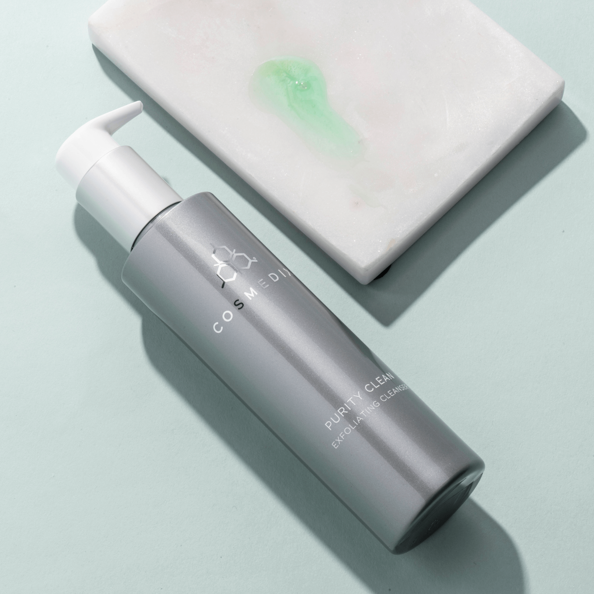 Cosmedix purity clean cleanser bottle with pump of product on a light blue background
