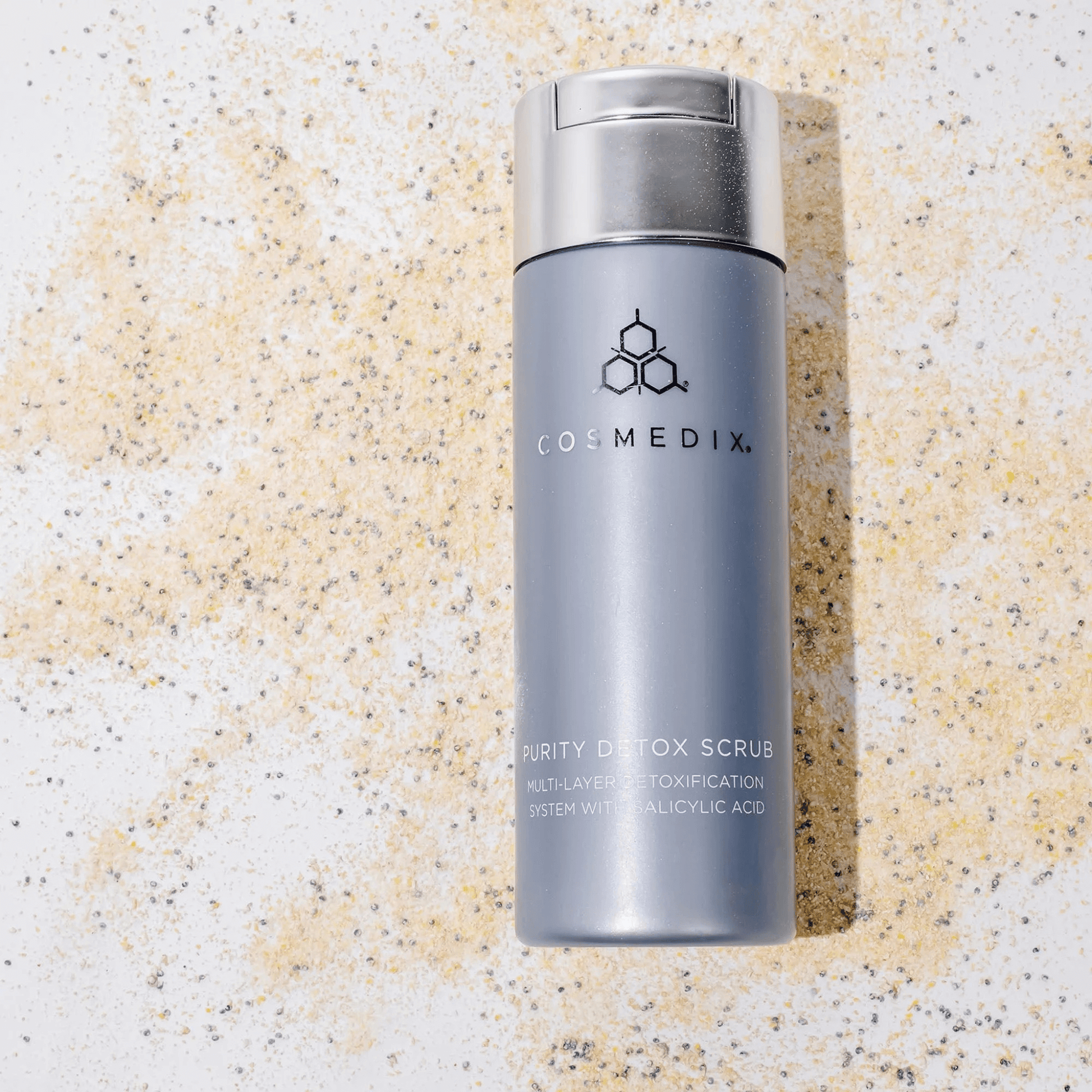 Cosmedix Purity Detox scrub bottle on a textured scrub background