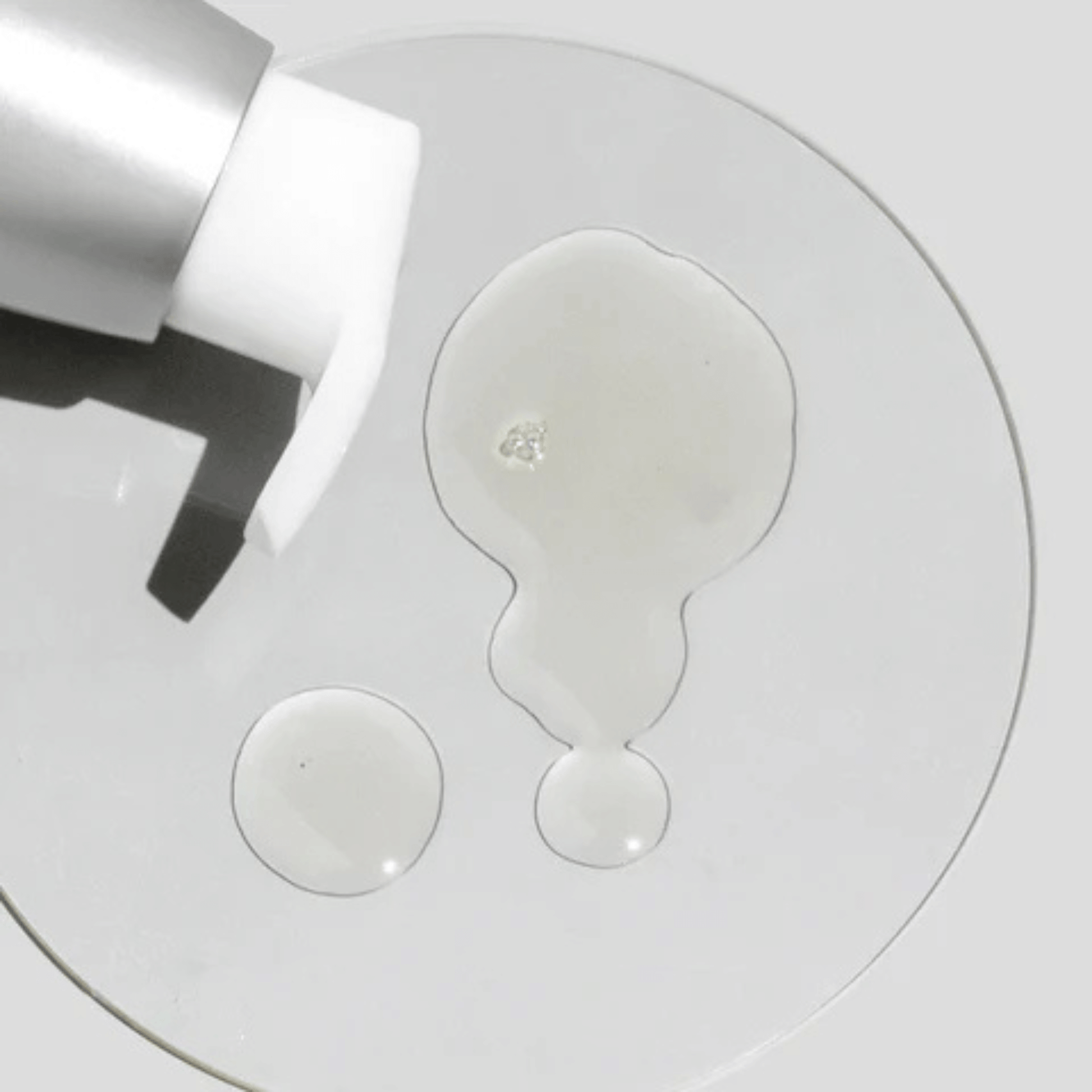 Close-up of Cosmedix Purity Clean cleansing oil with cleanser droplets on a white background