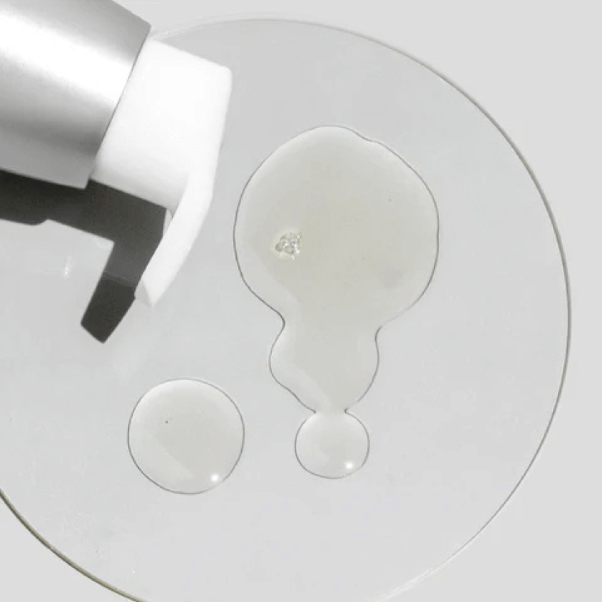 Close-up of Cosmedix Purity Clean cleansing oil with cleanser droplets on a white background