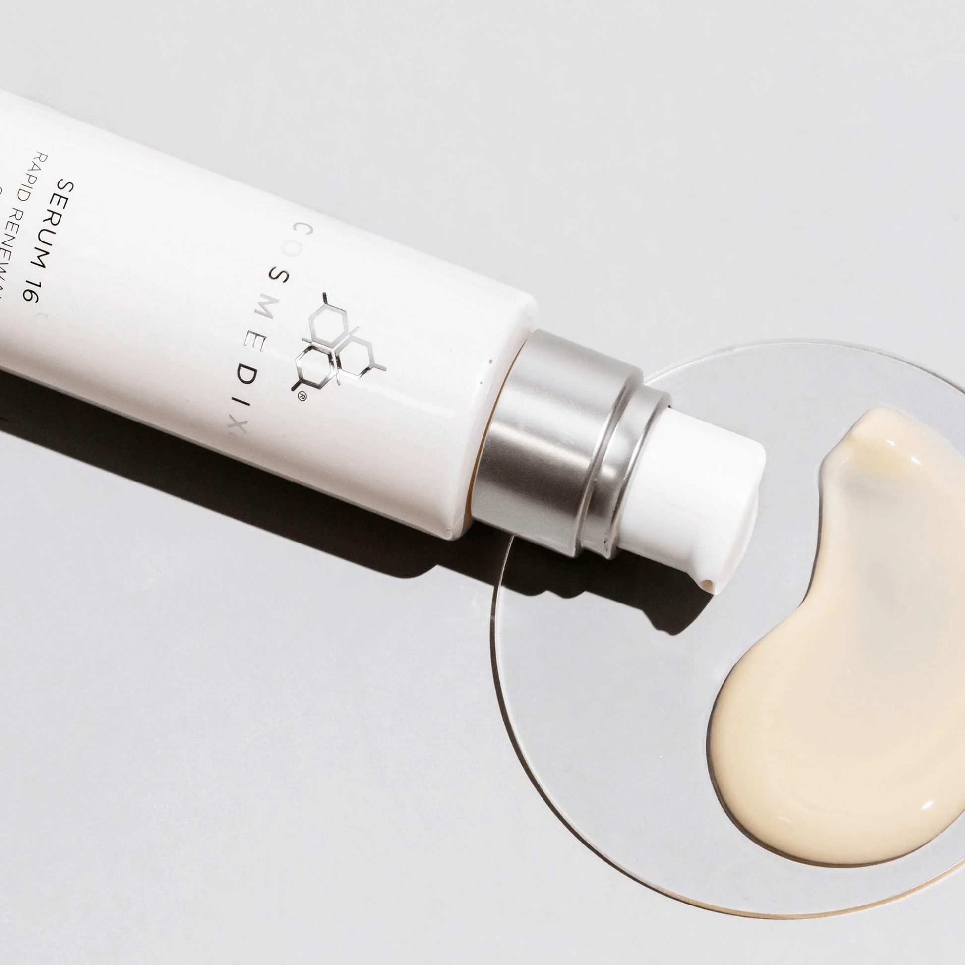 Serum 16 bottle with a droplet of cream on a light background