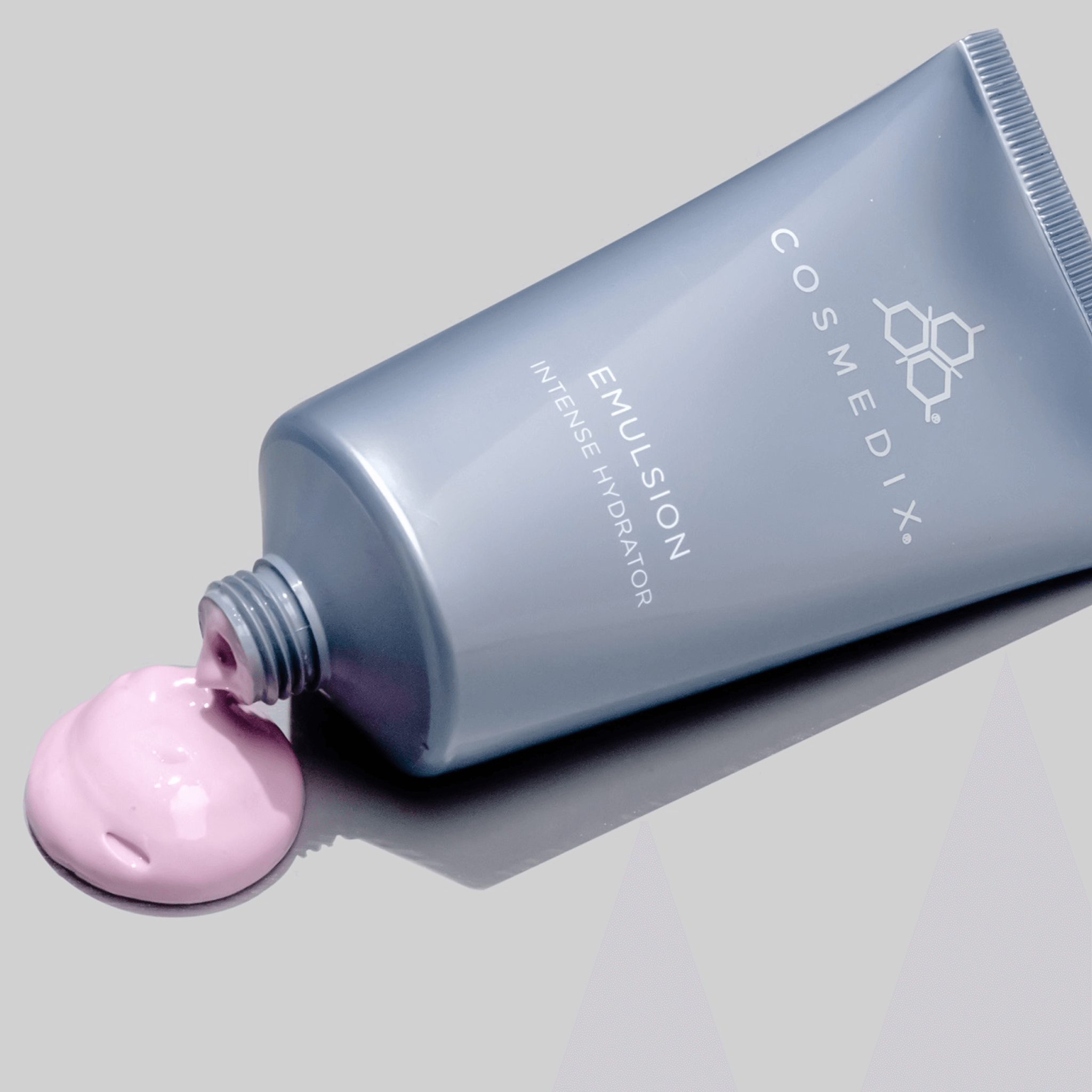 Cosmedix emulsion tube with pink cream on a grey background