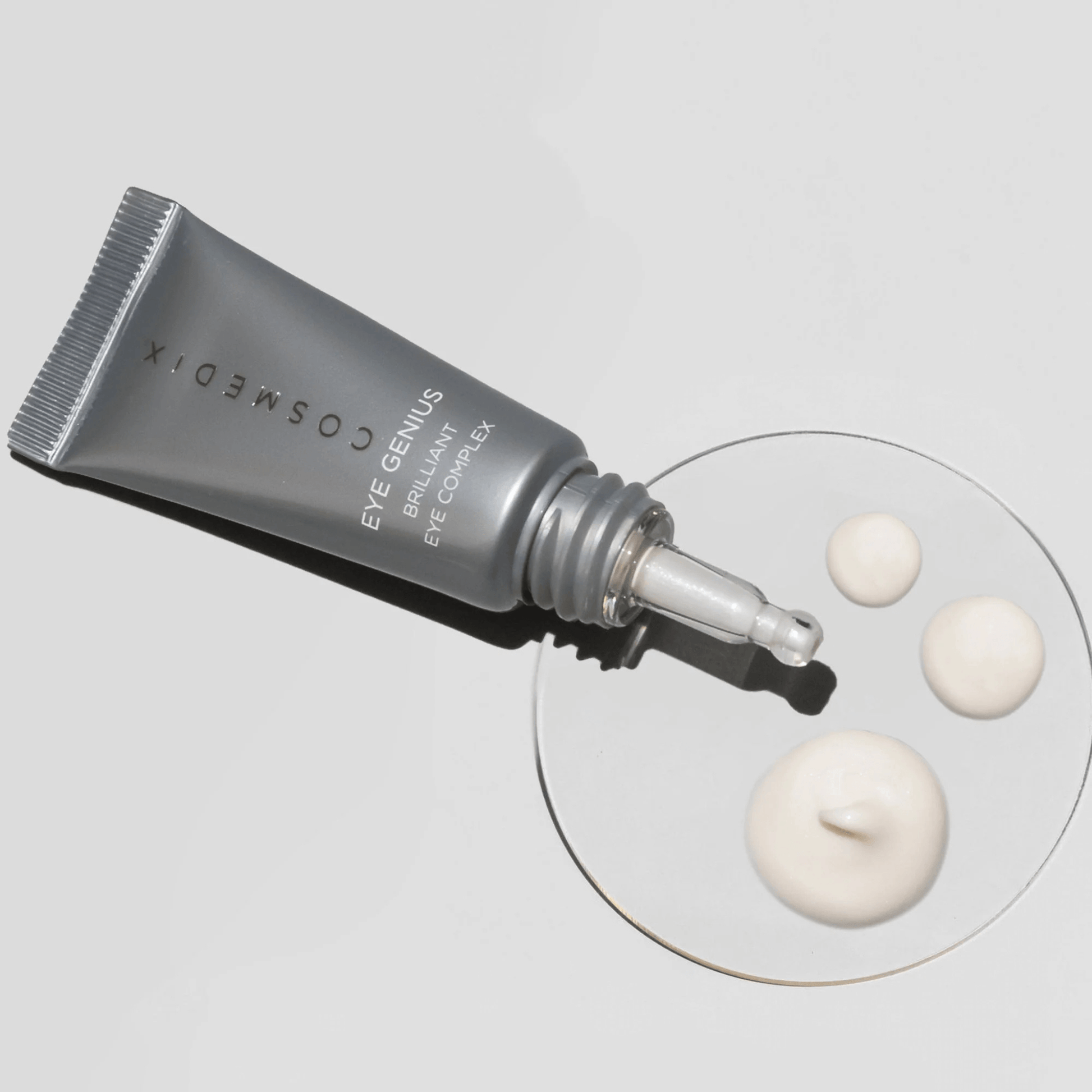 Cosmedix eye cream with applicator and three skincare swatches on a light grey background