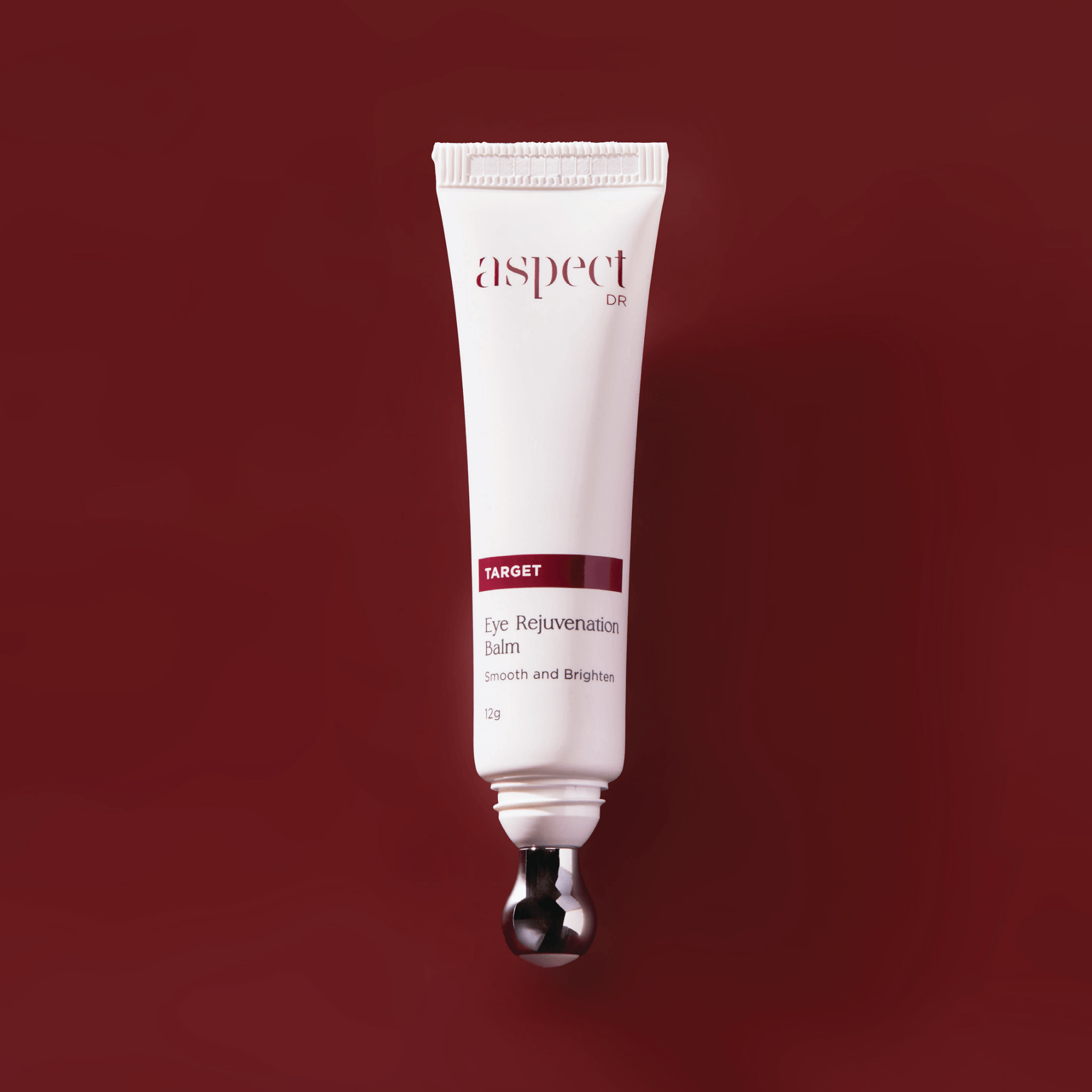 A white squeeze tube of Aspect Dr Target Eye Rejuvenation Balm with a metallic silver ball applicator, centered against a solid deep red background